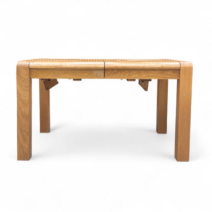 Three-quarter angle of the 'Bakerloo' Solid Oak Dining Table, highlighting the solid wood construction and robust leg structure.