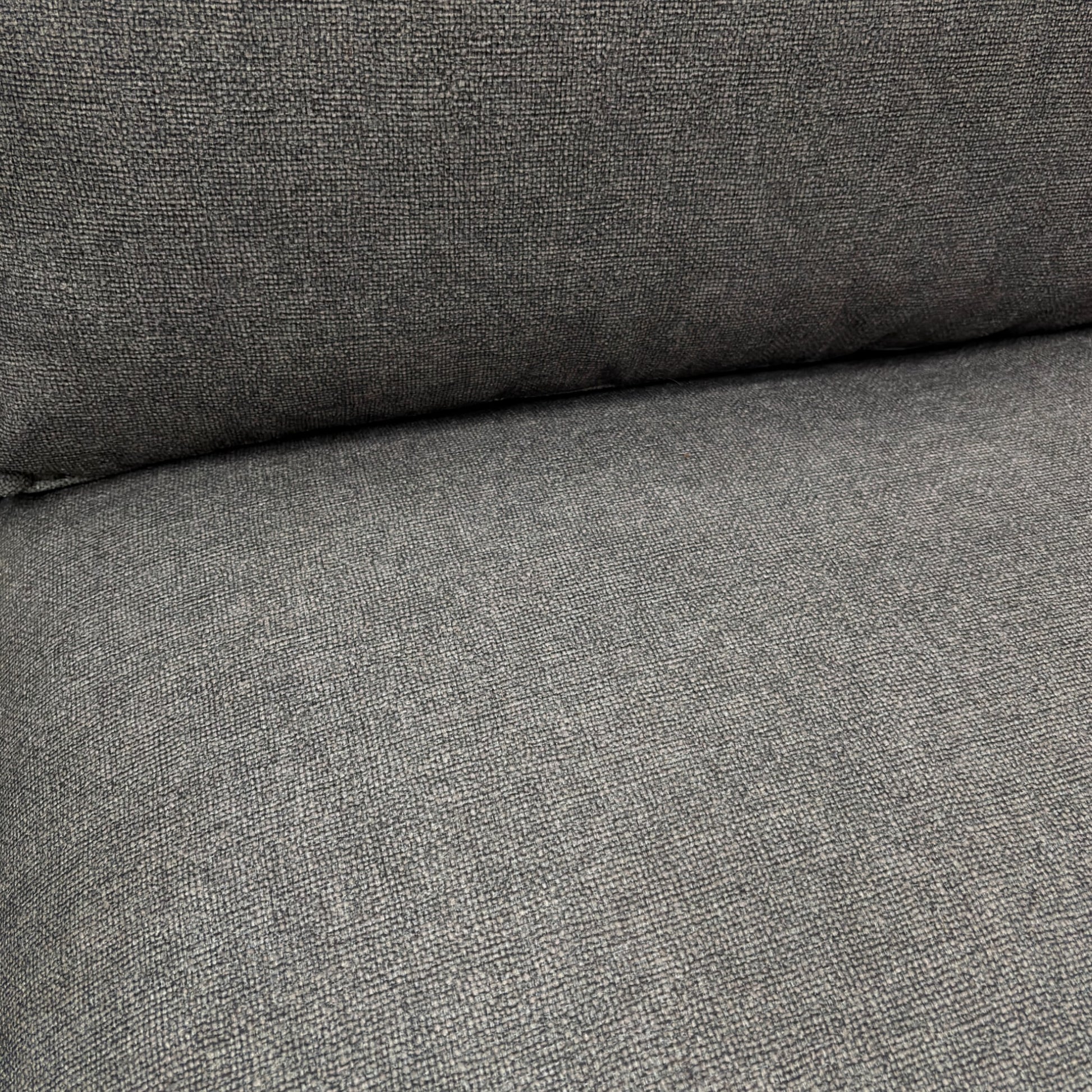Close-up detail of the charcoal grey tight weave fabric on the 'Gaia' sofa, showing the texture and modern feel of the upholstery.