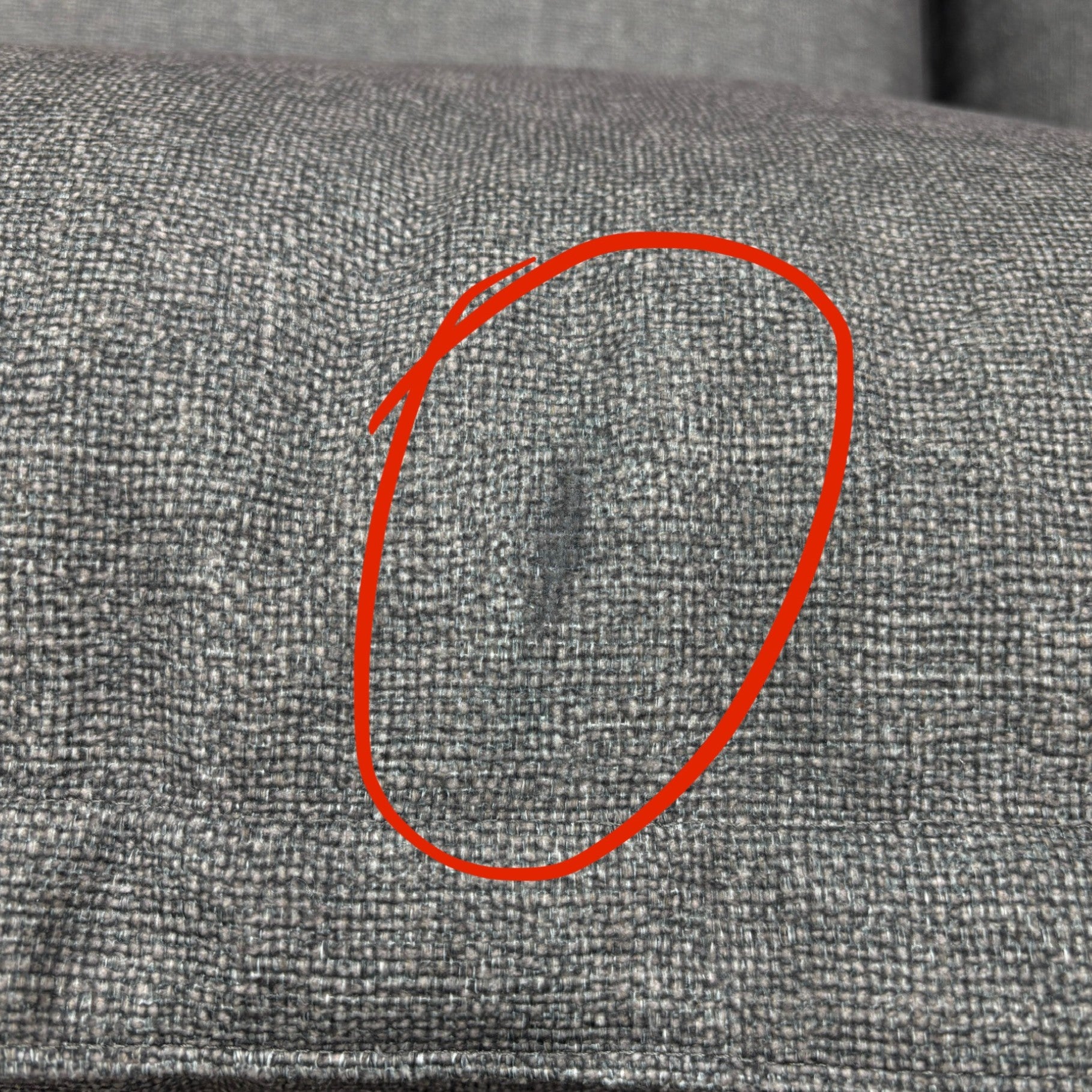 Close-up image highlighting the damage or imperfection on the 'Gaia' Charcoal Grey RHF Corner Sofa, as noted in the product description.