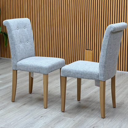 Augusta mist grey fabric pair of roll back upholstered dining chairs photographed against a slatted wooden wall