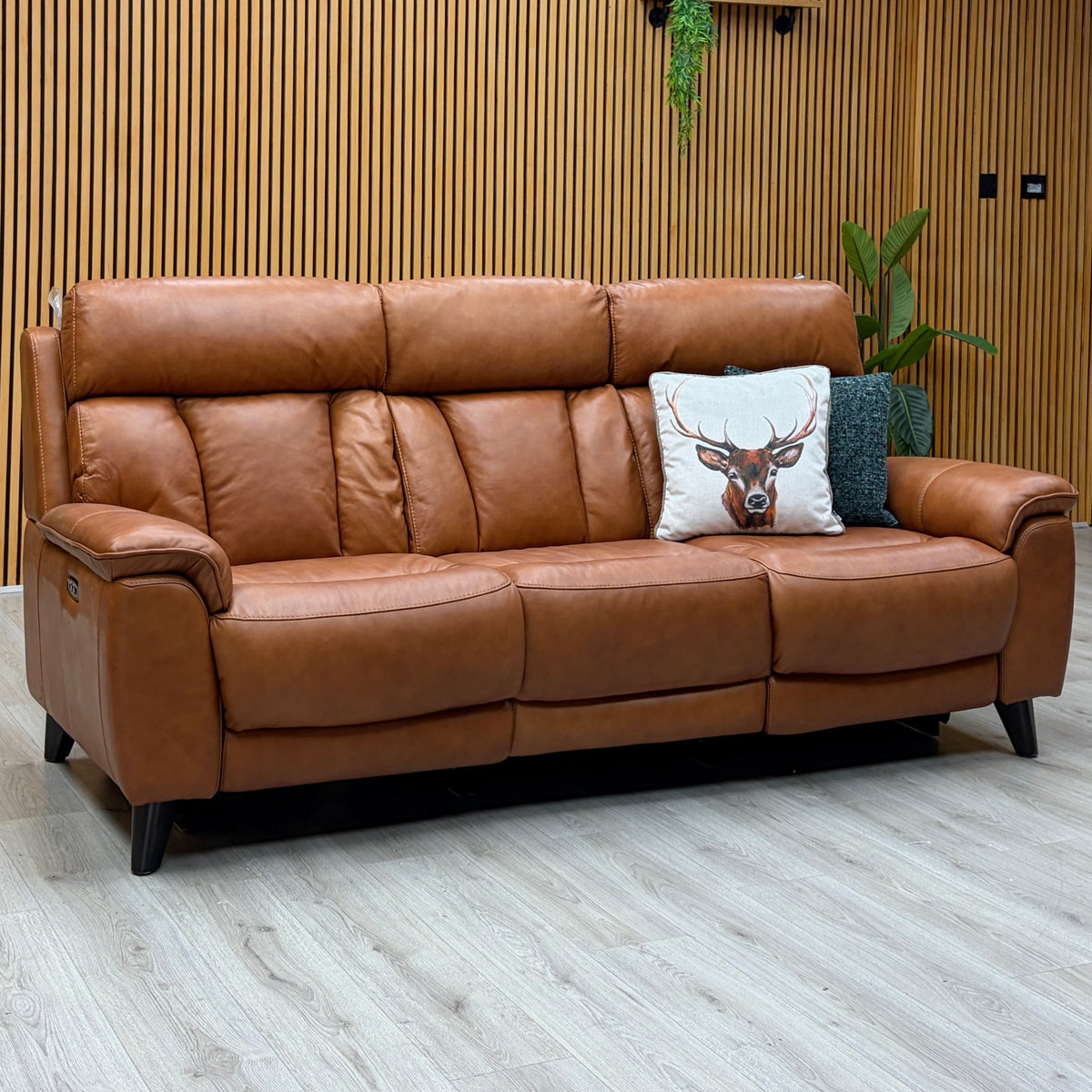 Dreamer saddle brown leather 3 seater sofa against a slatted wooden wall on a light oak floor