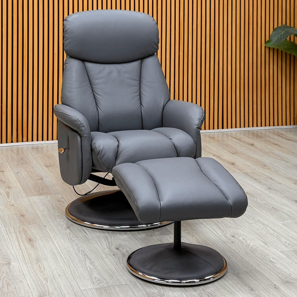 Elm petrol blue leather swivel recliner chair and footstool against a slatted wooden wall on a light oak floor