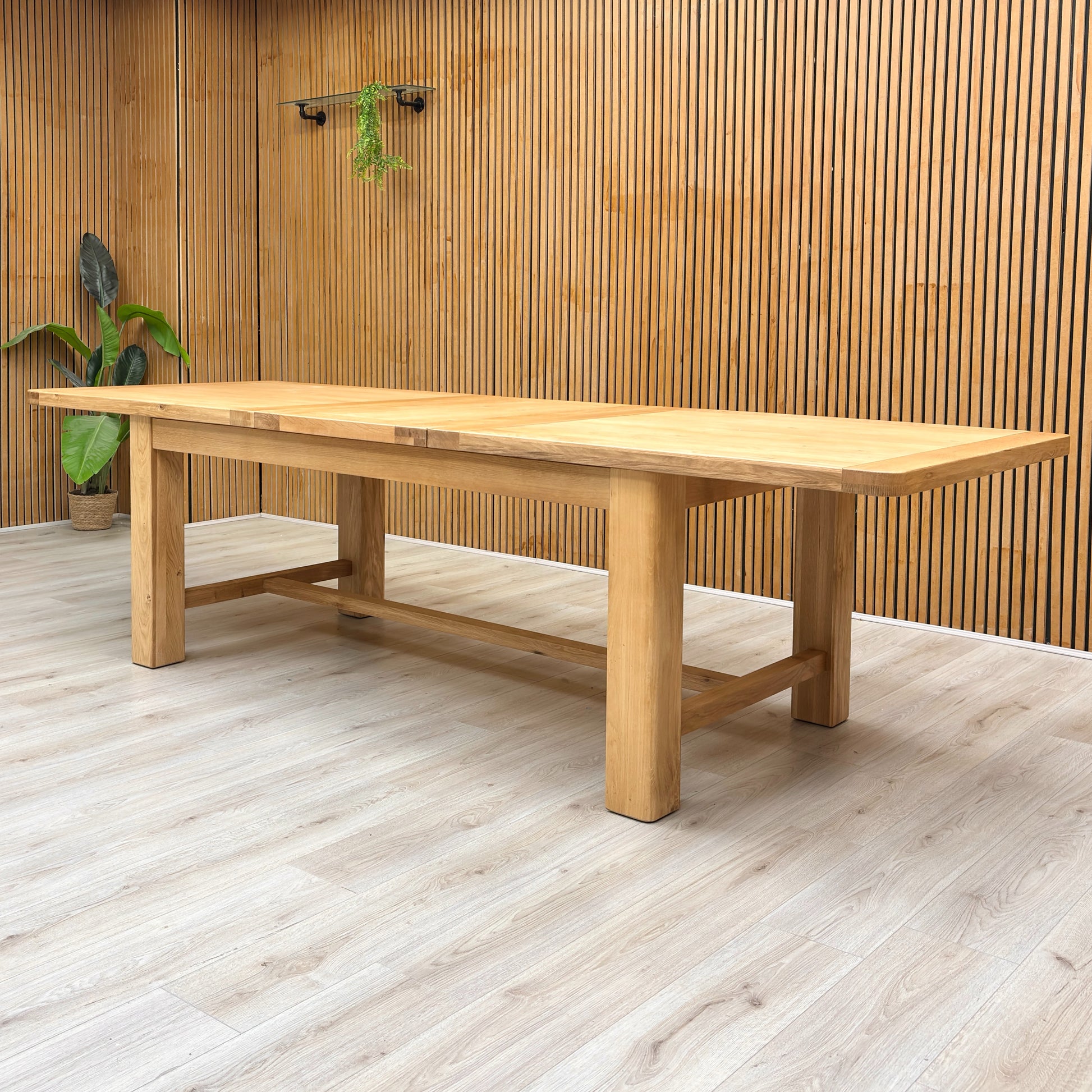 Lifestyle shot of the Augusta dining table in a modern dining room setting, showcasing its generous size and elegant oak finish.