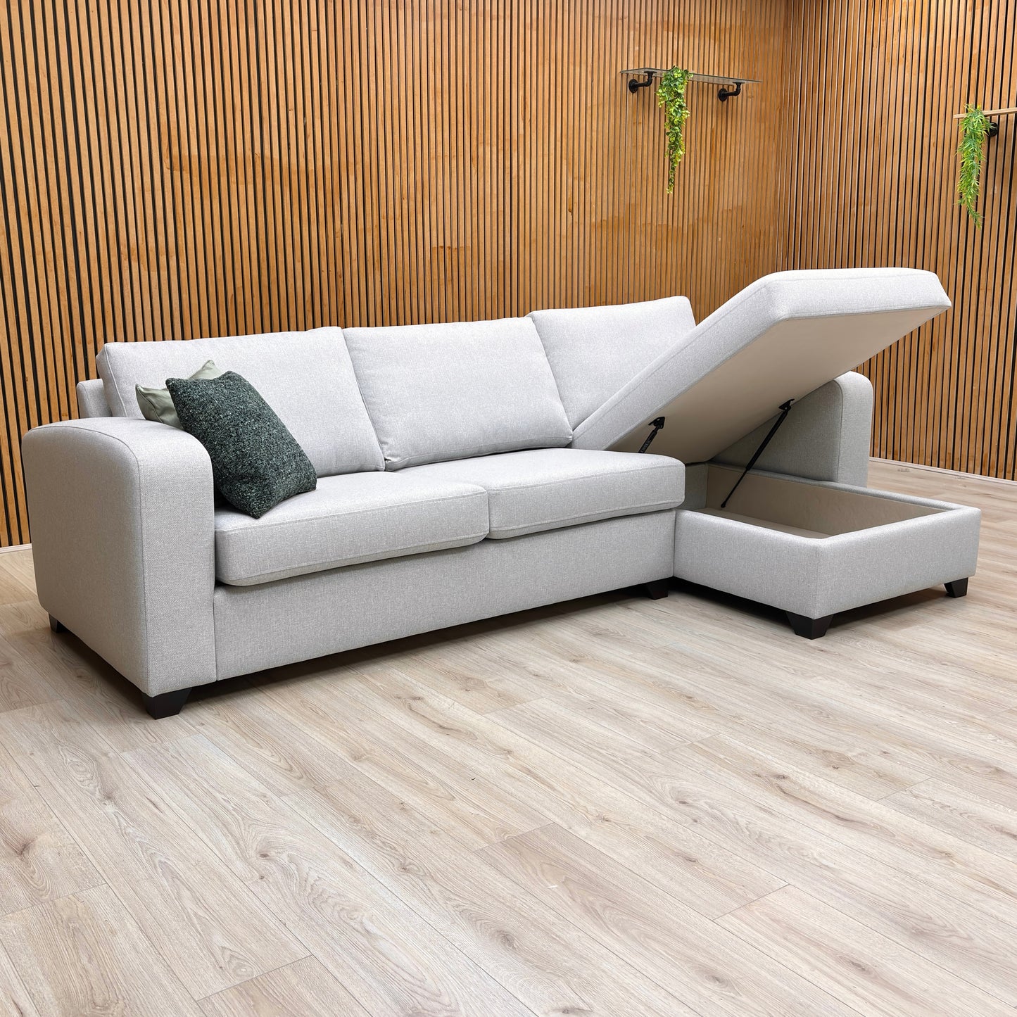 Lifestyle shot of the Layla sofa bed in a contemporary living room, highlighting its generous chaise seating and sleek silver upholstery.