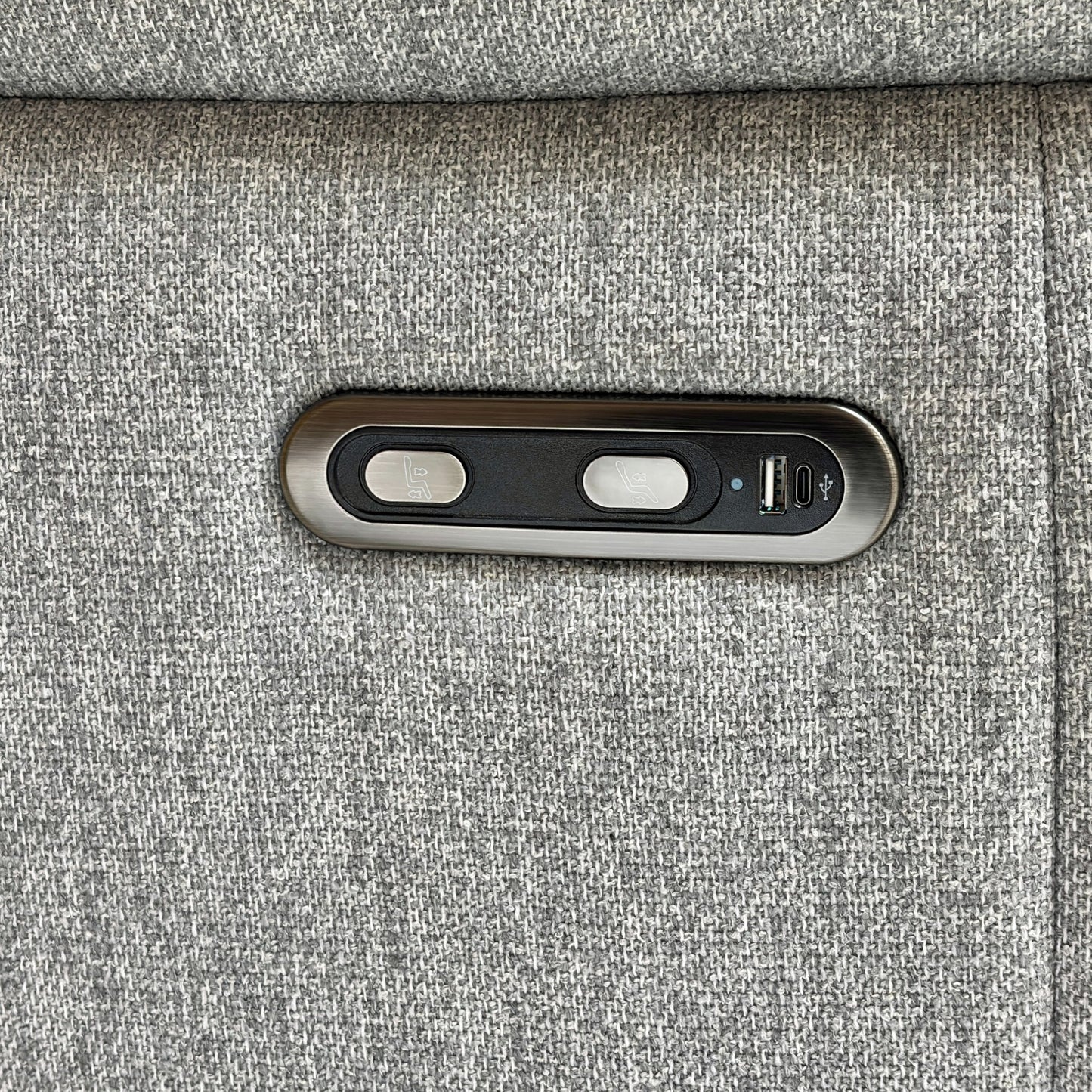 Close-up on the power recliner control button and USB charging port located on the side of the sofa arm.