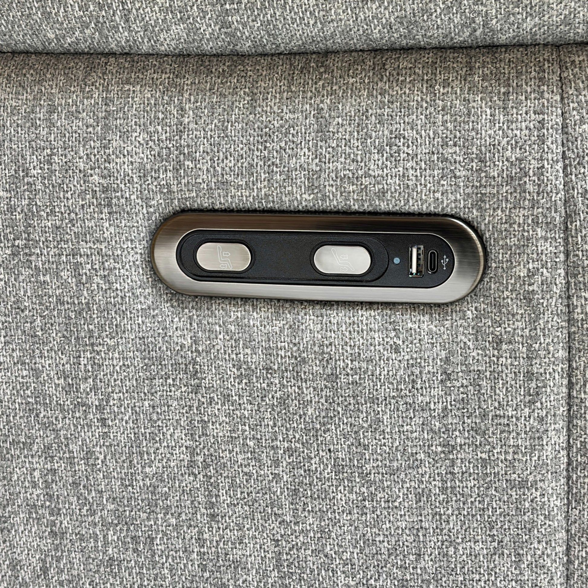 Close-up on the power recliner control button and USB charging port located on the side of the sofa arm.