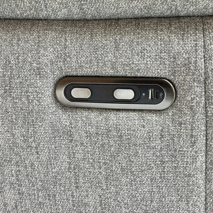 Close-up on the power recliner control button and USB charging port located on the side of the sofa arm.