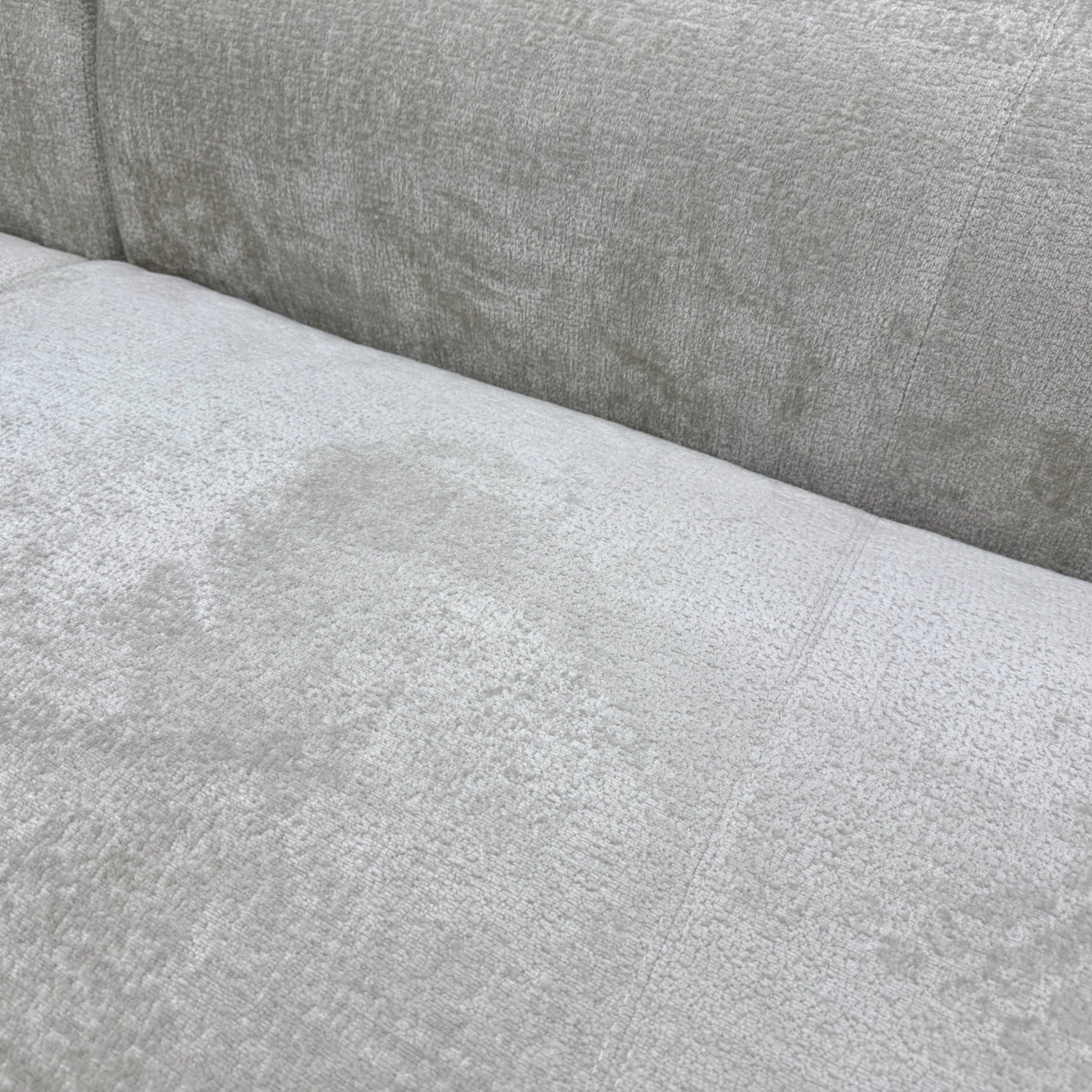 Close-up texture detail of the soft turtledove grey chenille fabric upholstery on the 'Los Angeles' sofa.