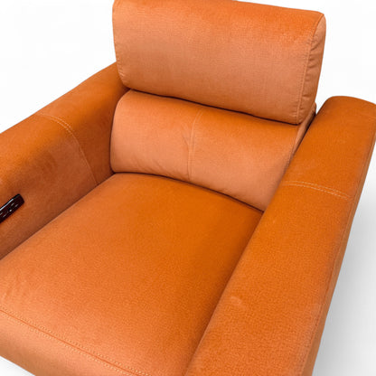 Close-up texture shot of the plush rust orange velvet upholstery on the 'Ezra' power recliner chair.