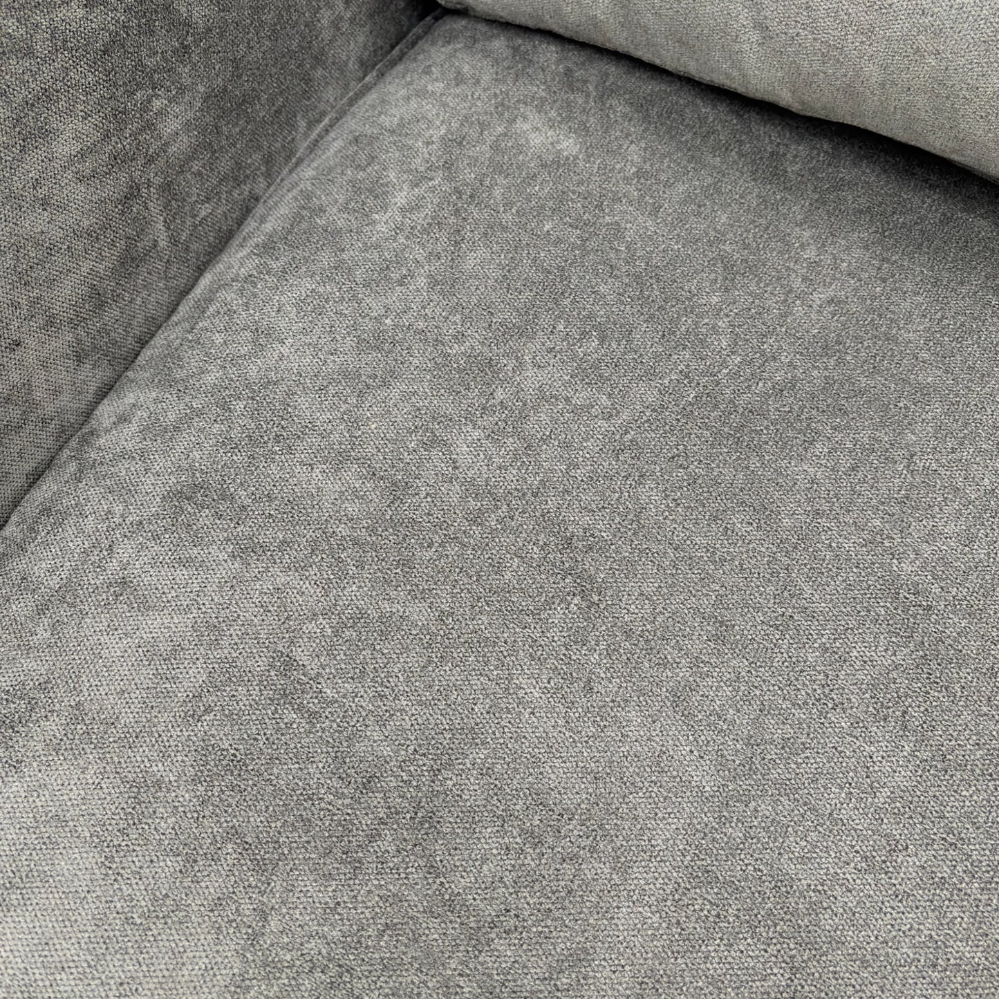 Close-up on the base and modern wooden feet of the grey fabric sofa.