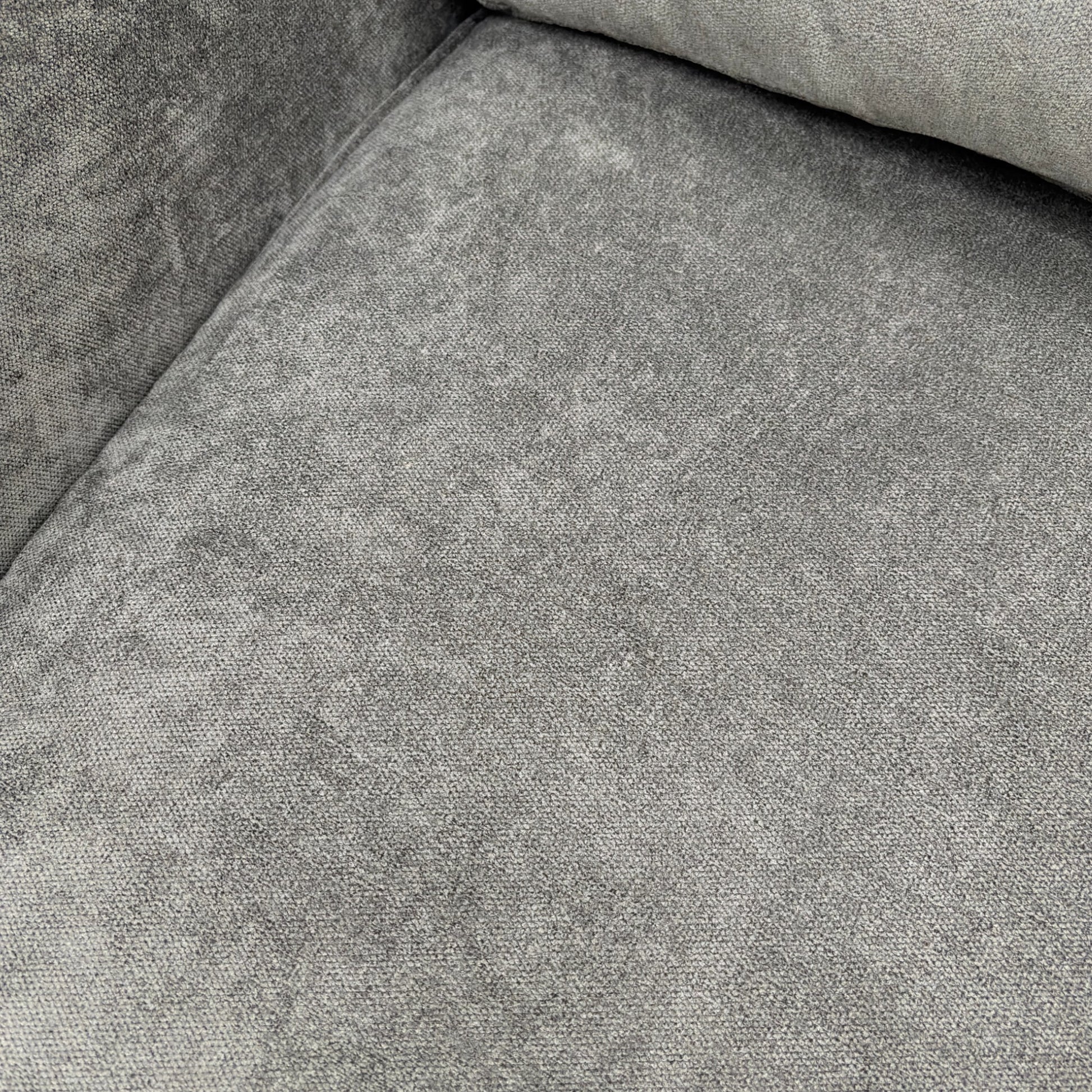 Close-up on the base and modern wooden feet of the grey fabric sofa.