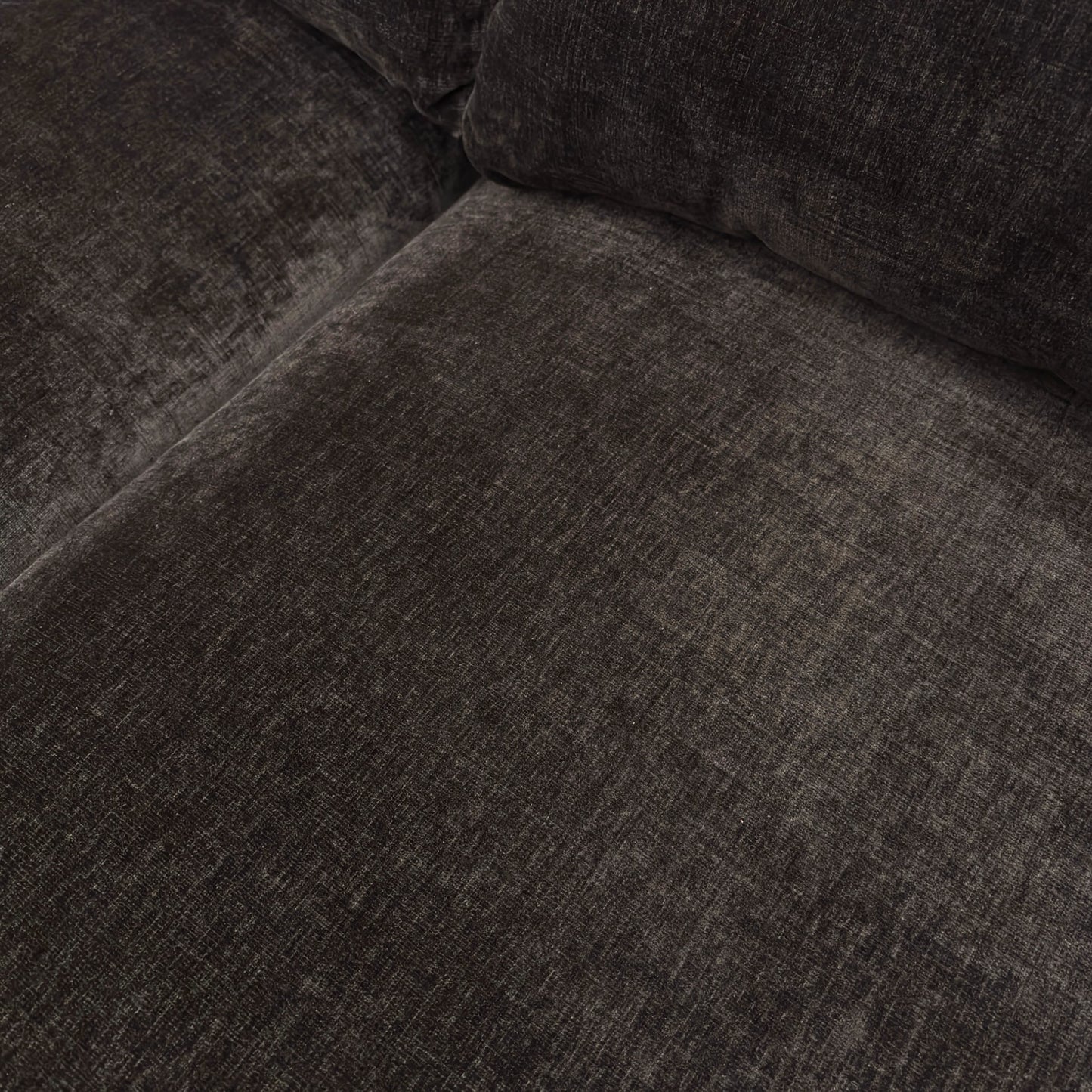 Close-up texture detail of the ribbed dark chocolate chenille fabric and the stitching on the sofa.