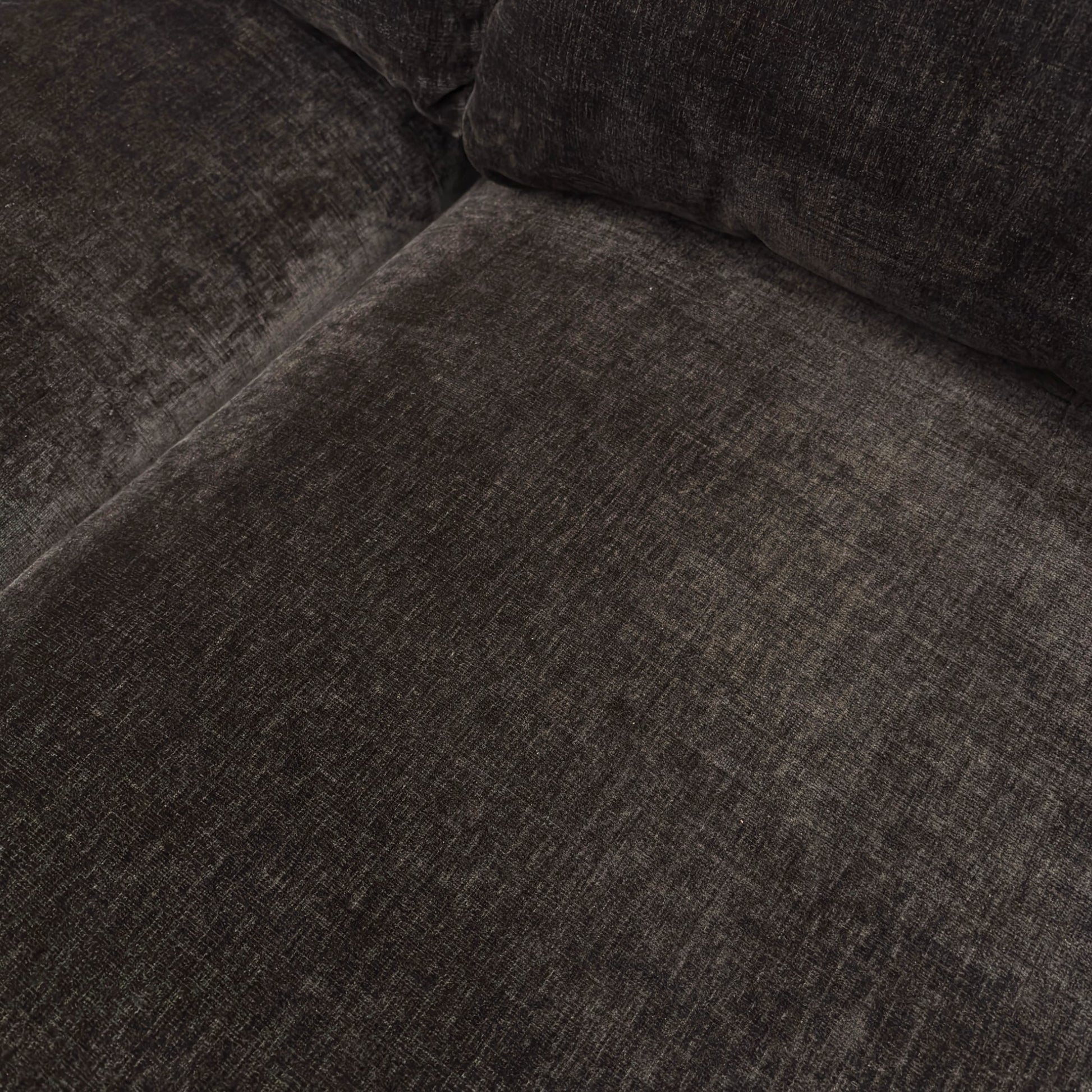 Close-up texture detail of the ribbed dark chocolate chenille fabric and the stitching on the sofa.