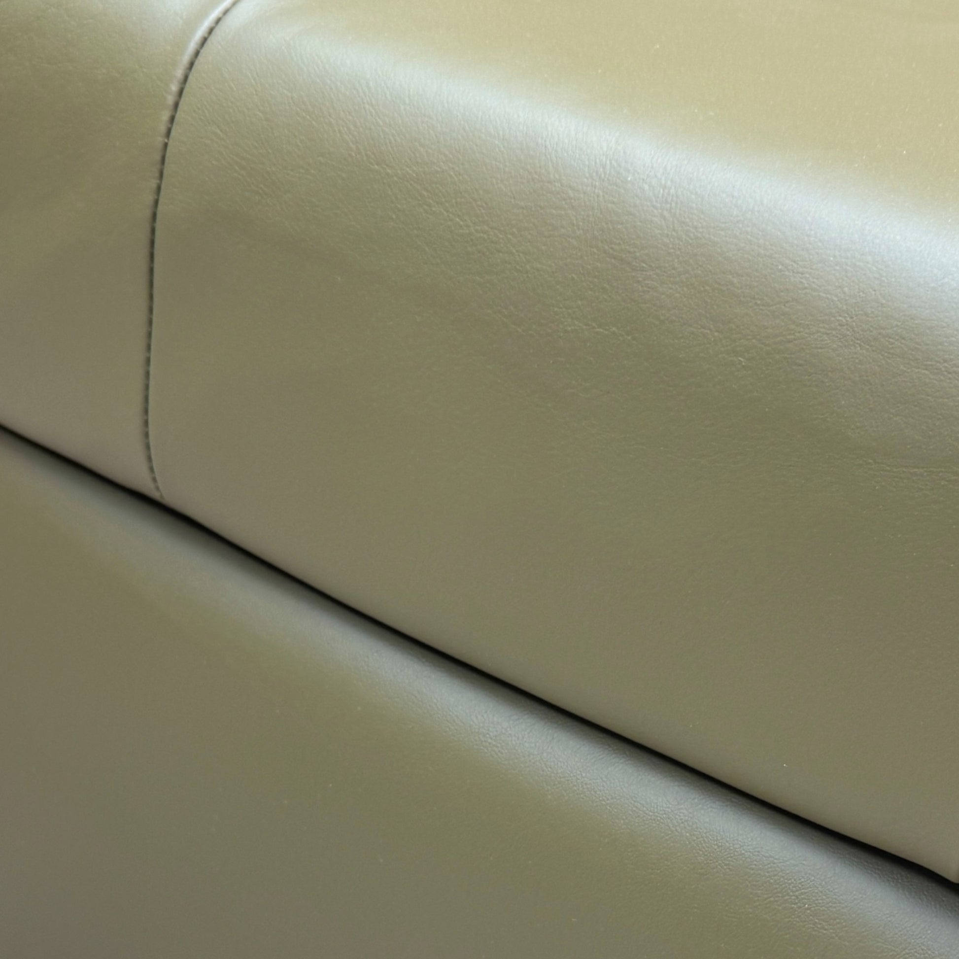 Close-up shot of the top surface of the 'Ava' footstool, showing the texture and quality of the khaki green leather upholstery.