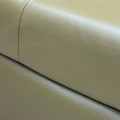 Close-up shot of the top surface of the 'Ava' footstool, showing the texture and quality of the khaki green leather upholstery.