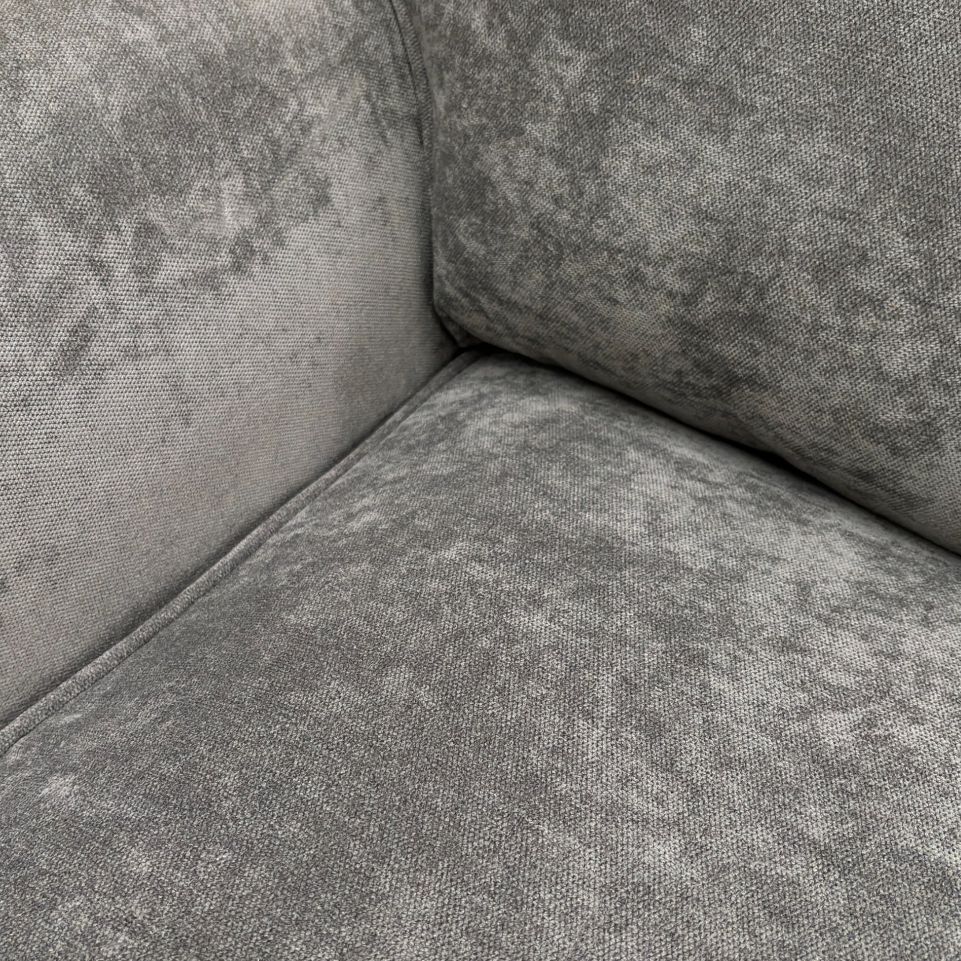 A close-up shot focusing on the texture of the grey fabric and the detail of the stitching on the cushions and arms.
