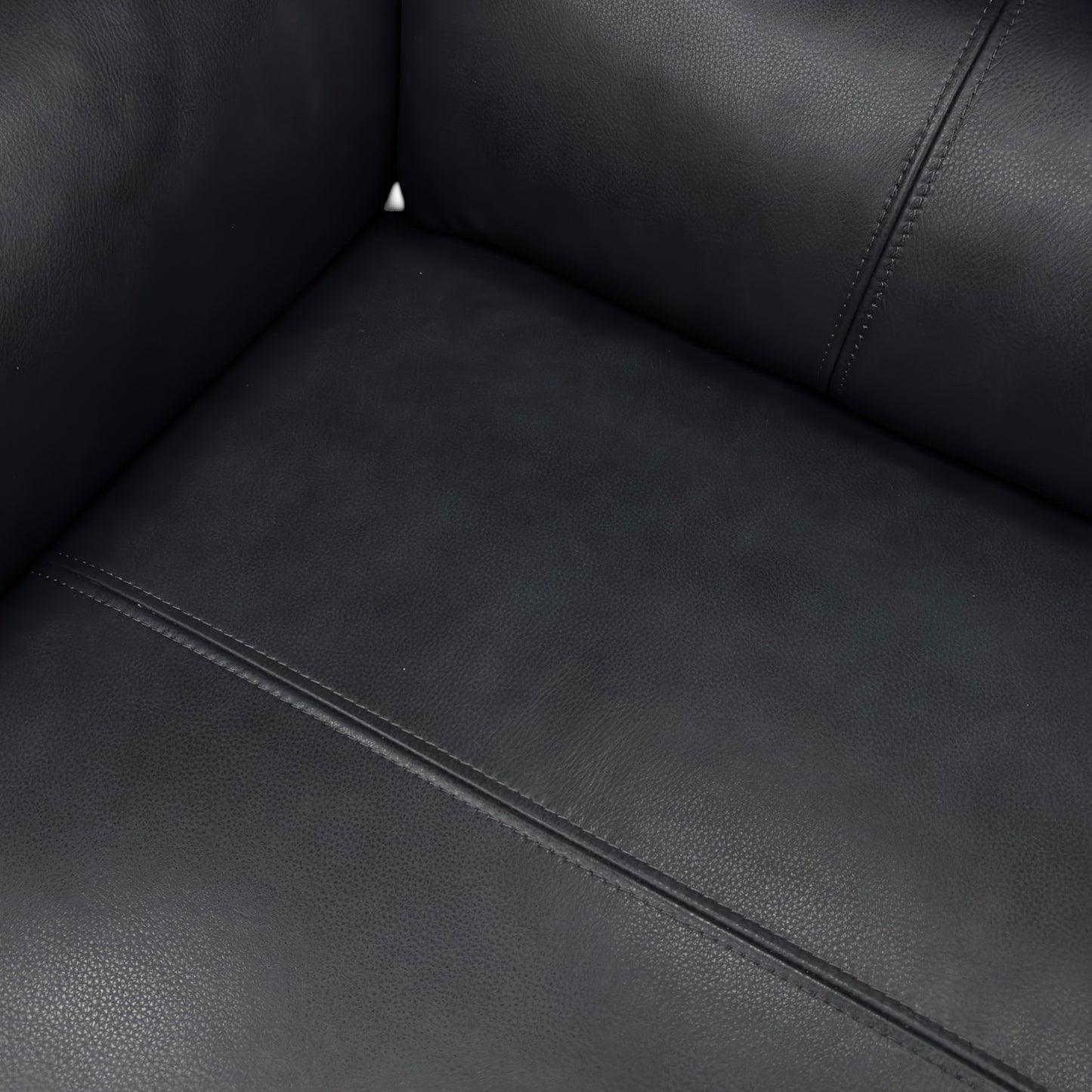 A close-up shot focusing on the seat cushion, the pocket spring detail, and the buttery-soft navy leather texture.