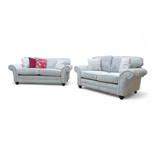 Angled view of the larger 'Clara' 3-seater sofa, highlighting the design details, scroll arms, and included scatter cushions.