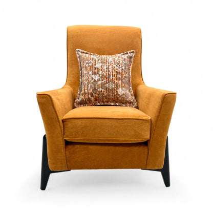 front view of the 'Collins' armchair, emphasizing the soft texture of the almond orange velvet and the contemporary silhouette.