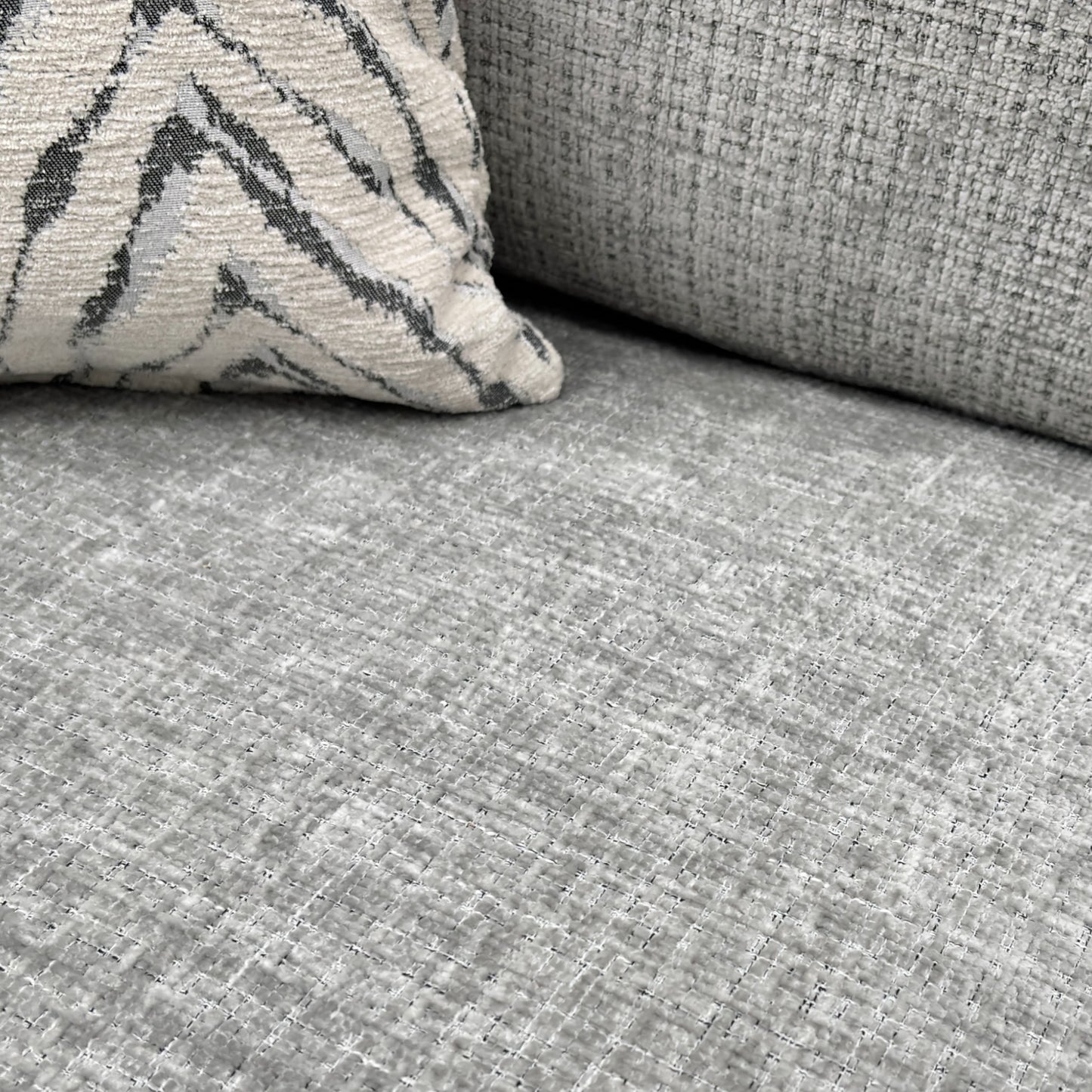 A close-up shot focusing on the seat and back cushions and the woven texture of the silver fabric.