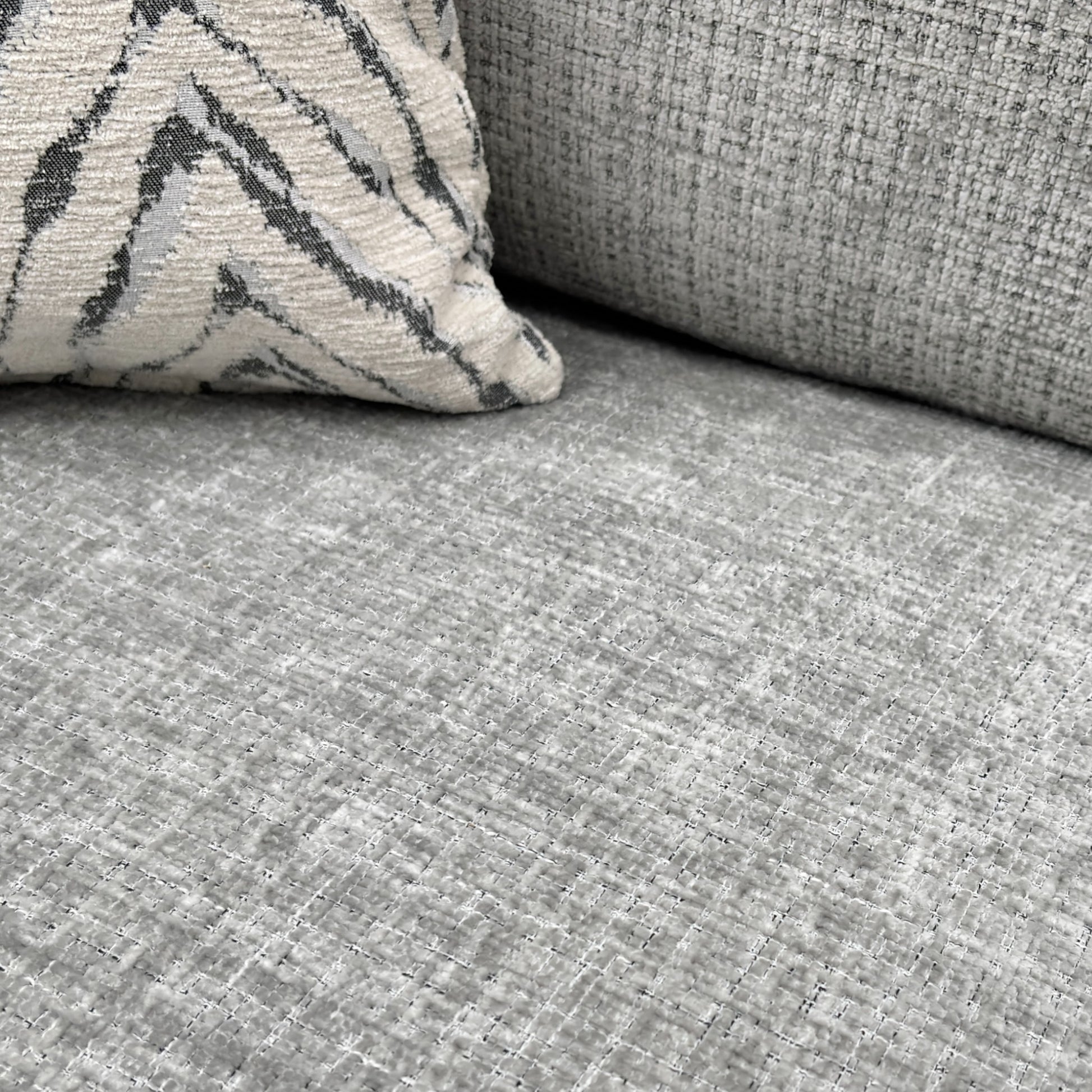 A close-up shot focusing on the seat and back cushions and the woven texture of the silver fabric.