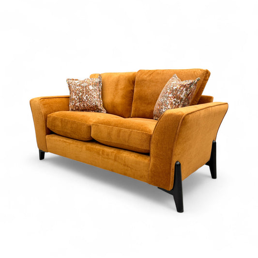 Slightly angled view of the 'Collins' 2 Seater Sofa, highlighting the plush texture of the almond orange towel velvet and two included accent cushions.