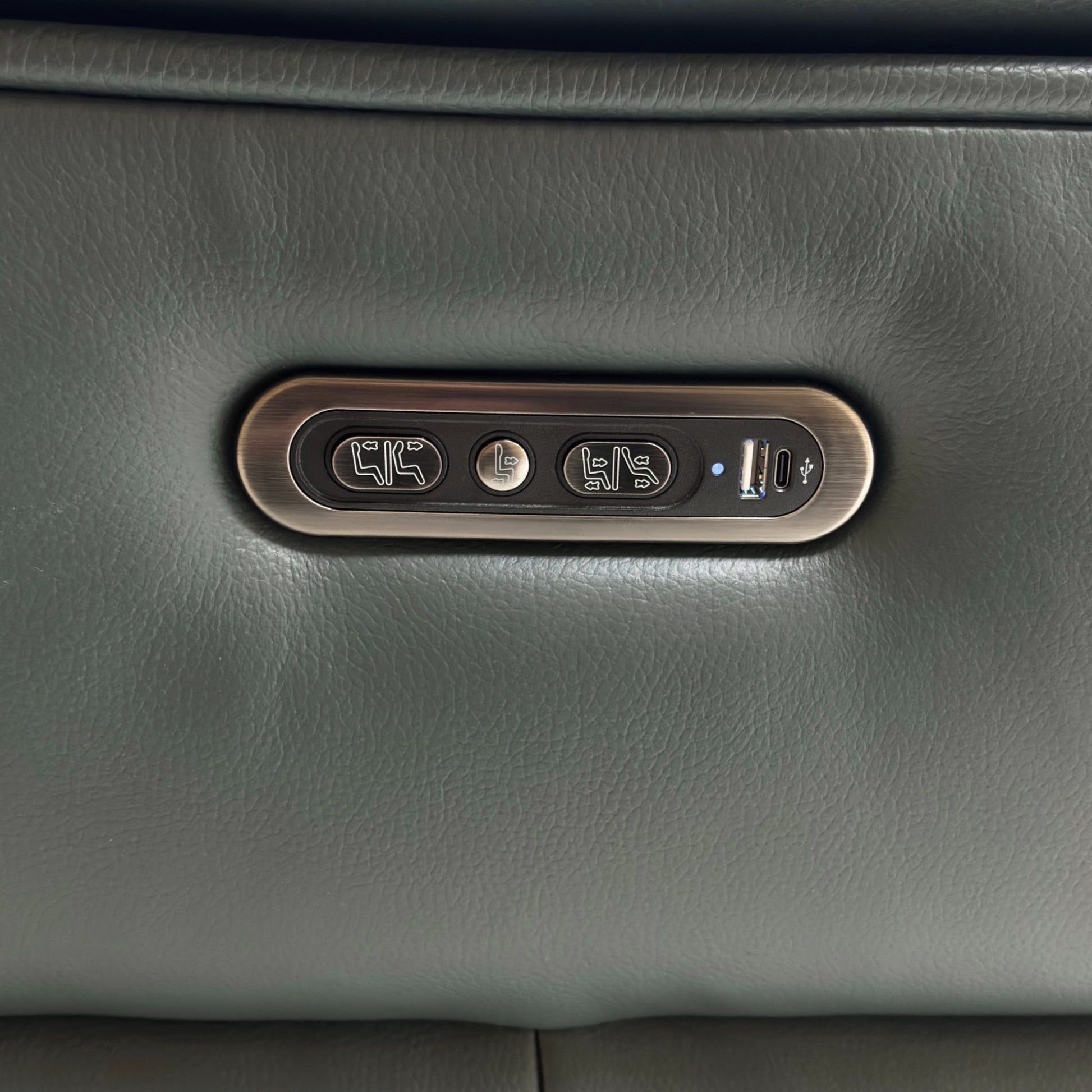 A close-up on the end armrest, showcasing the control panel with buttons for the power recline, headrest, and the integrated USB charging port.