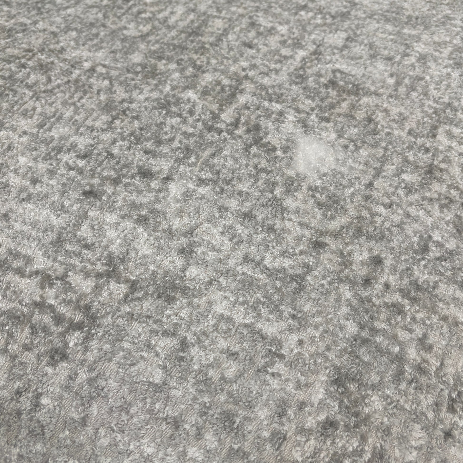 A close-up shot focusing on the armrest, the silver fabric texture, and how the scatter cushions sit on the main sofa.