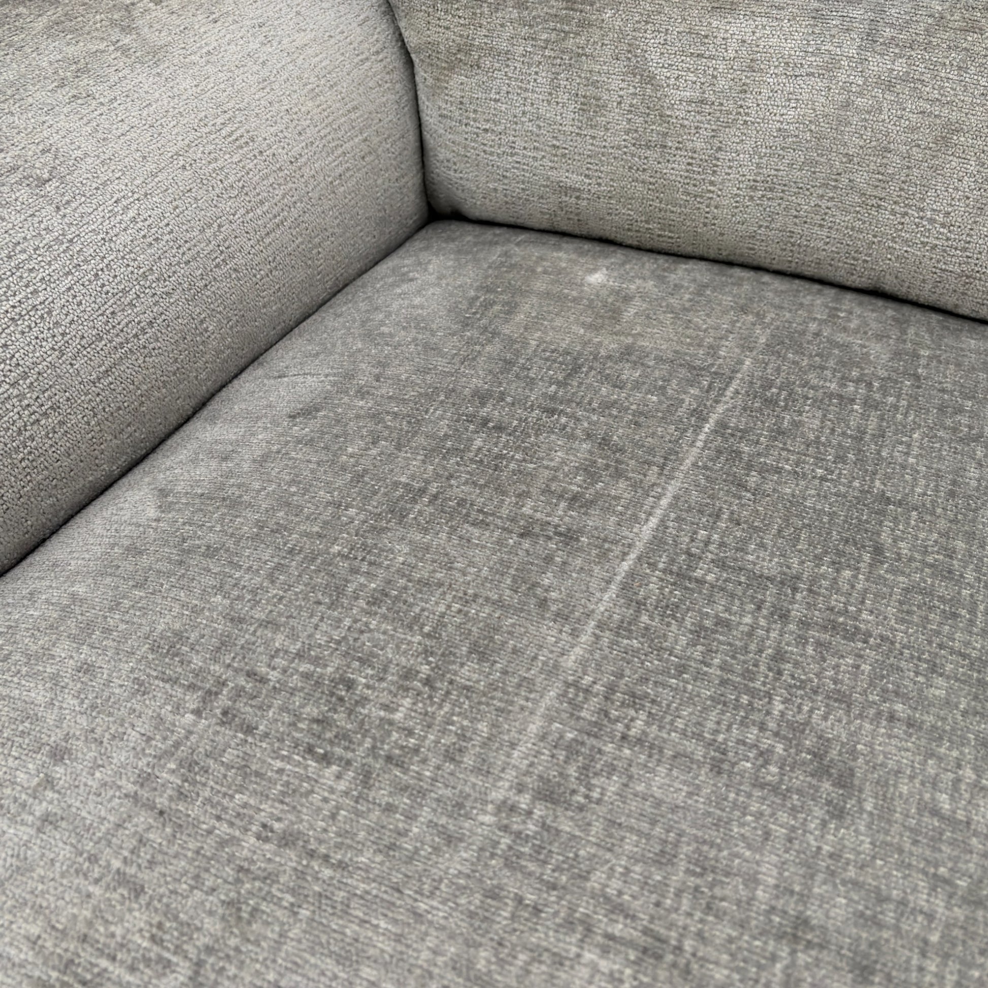 A close-up shot focusing on the texture and color of the dove grey fabric upholstery.
