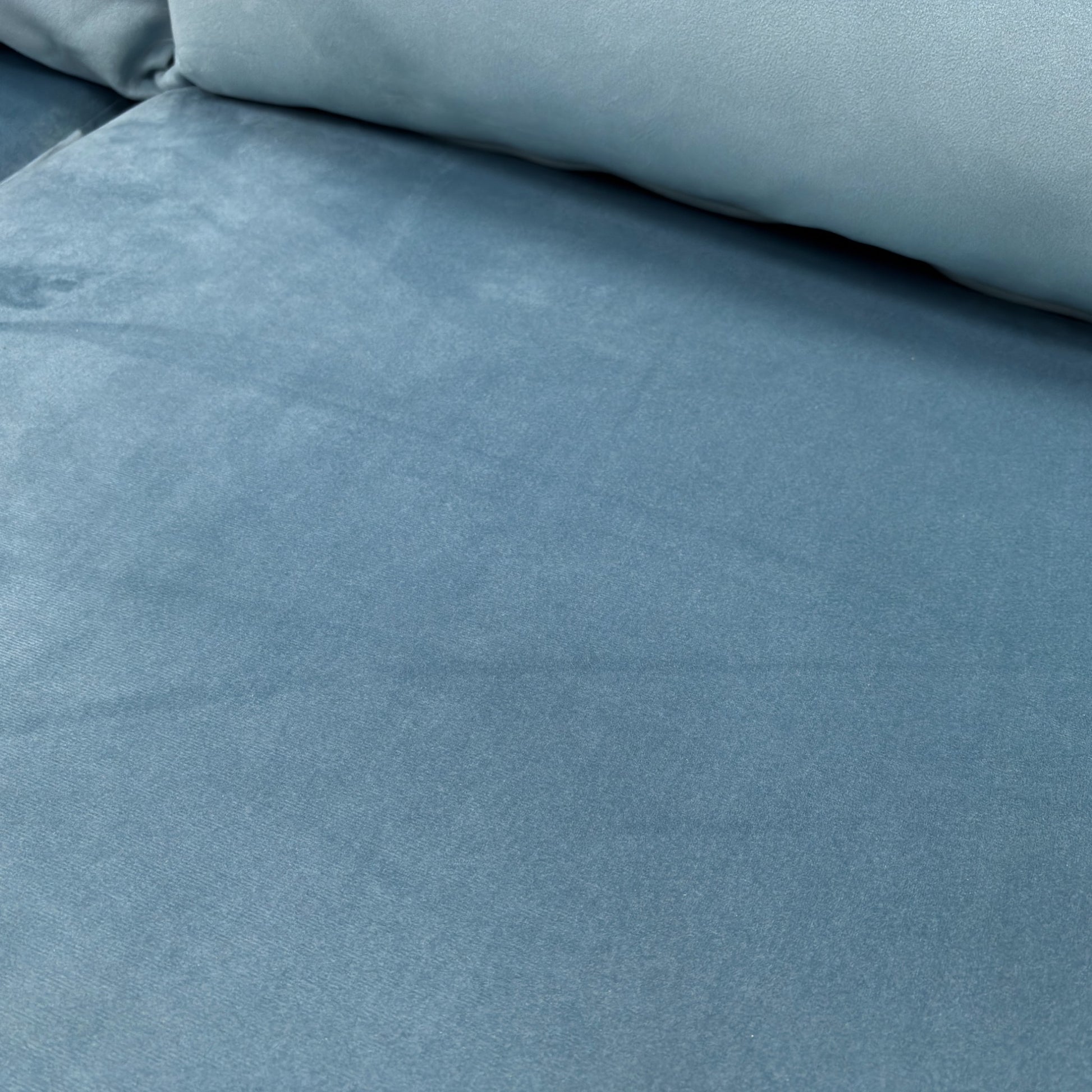 A close-up shot focusing on the Sky Velvet fabric and the button detailing on the back cushions.