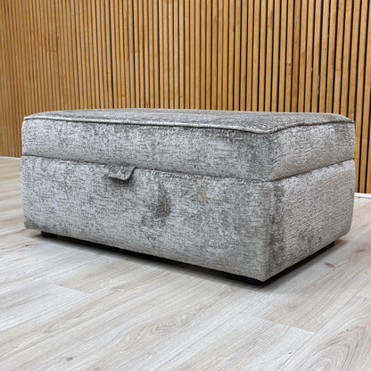 Lifestyle view for the Sasha storage footstool, highlighting the premium Alexandra Grey chenille upholstery, spacious internal storage, and durable hinge mechanism.
