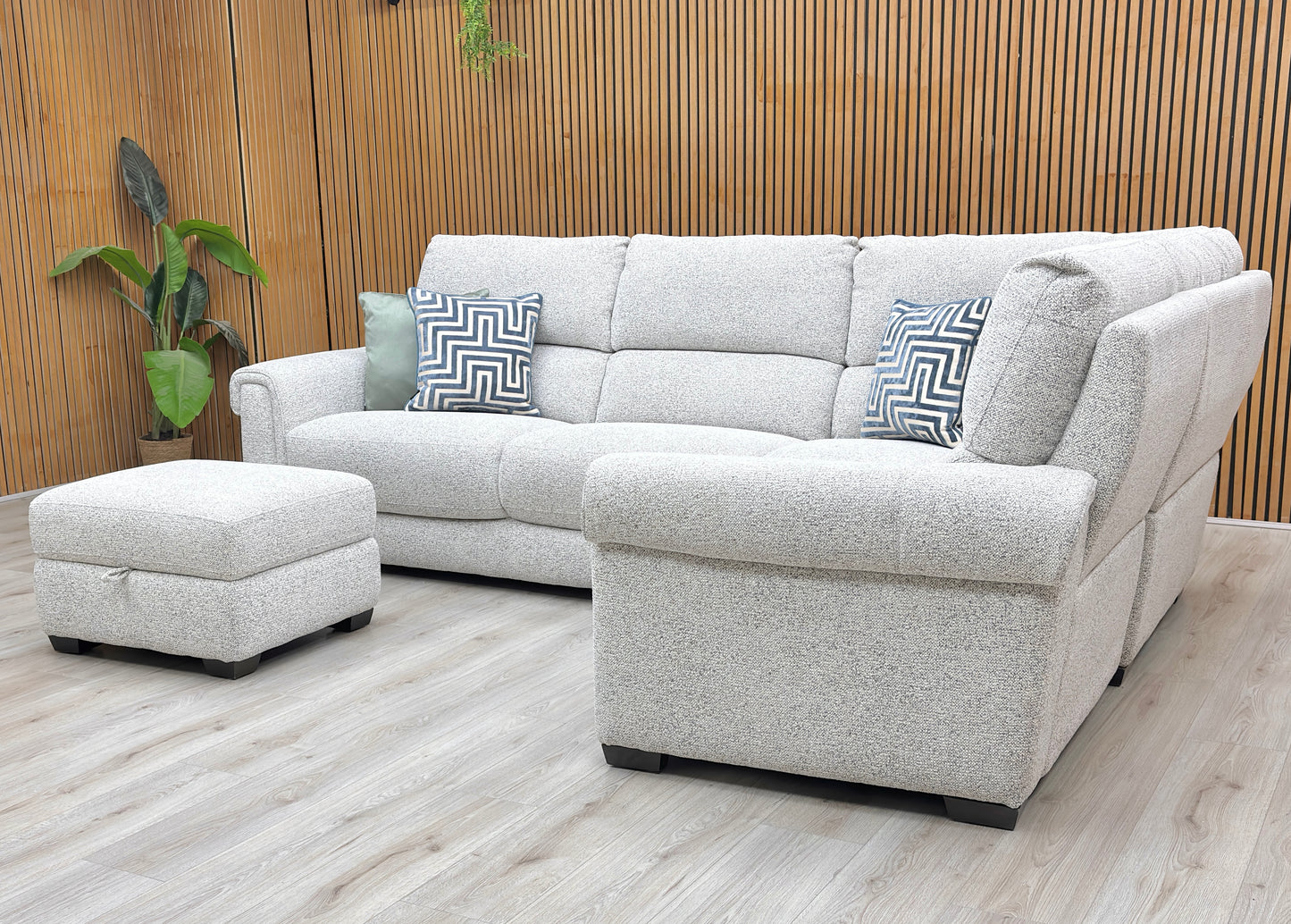 Lifestyle view of the Nixon corner sofa, highlighting the premium Oyster fabric, spacious L-shaped configuration, and hidden storage within the footstool.