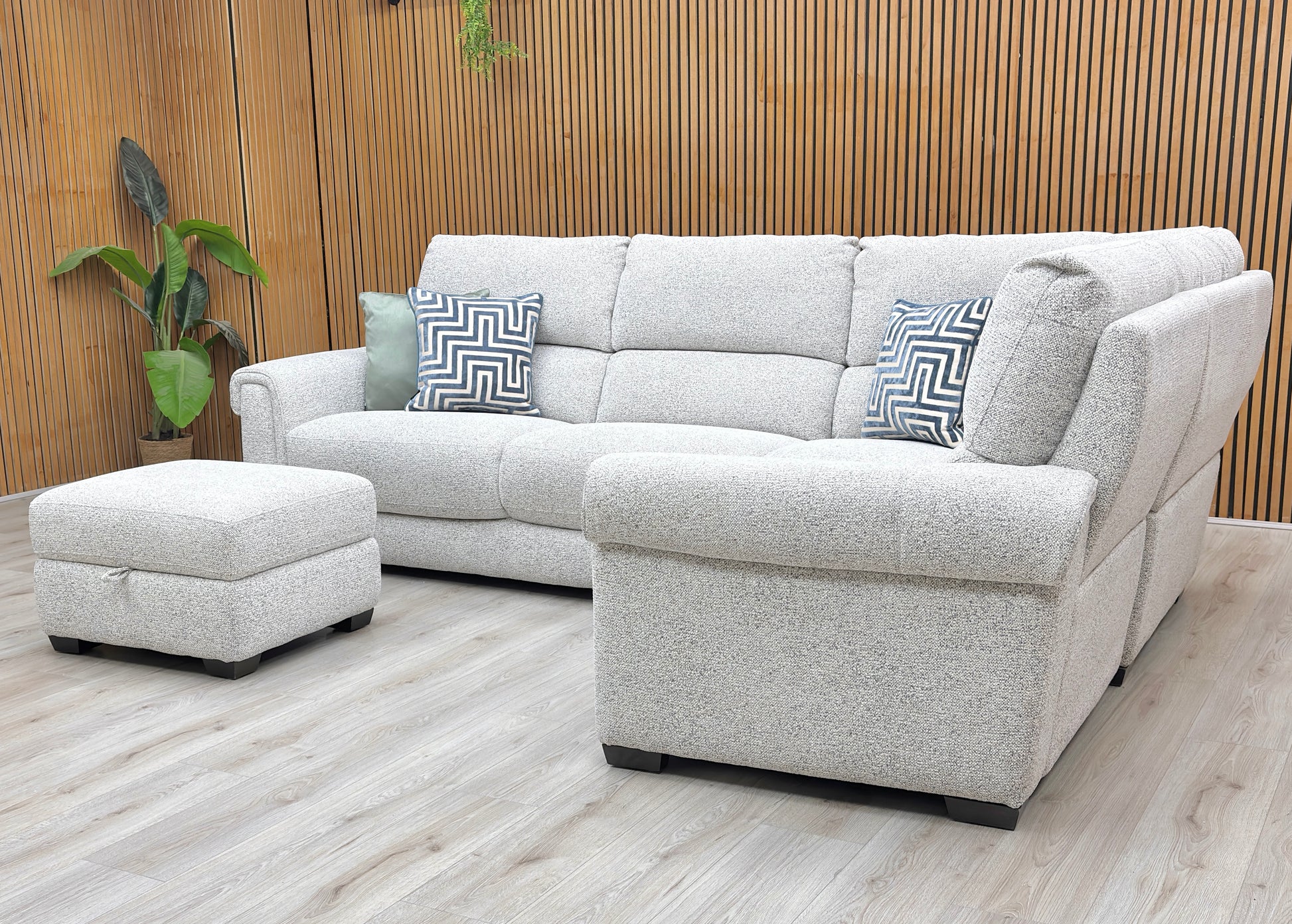 Lifestyle view of the Nixon corner sofa, highlighting the premium Oyster fabric, spacious L-shaped configuration, and hidden storage within the footstool.
