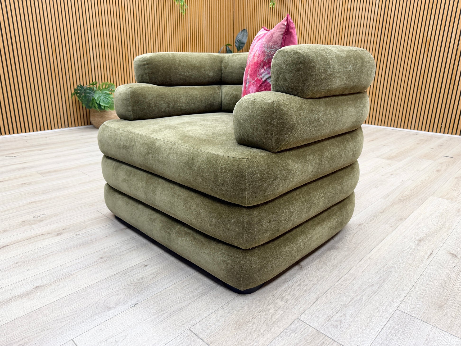 Lifestyle shot of the ‘Stacked’ armchair in a contemporary living room, showcasing its rich olive tone and cozy seating area.