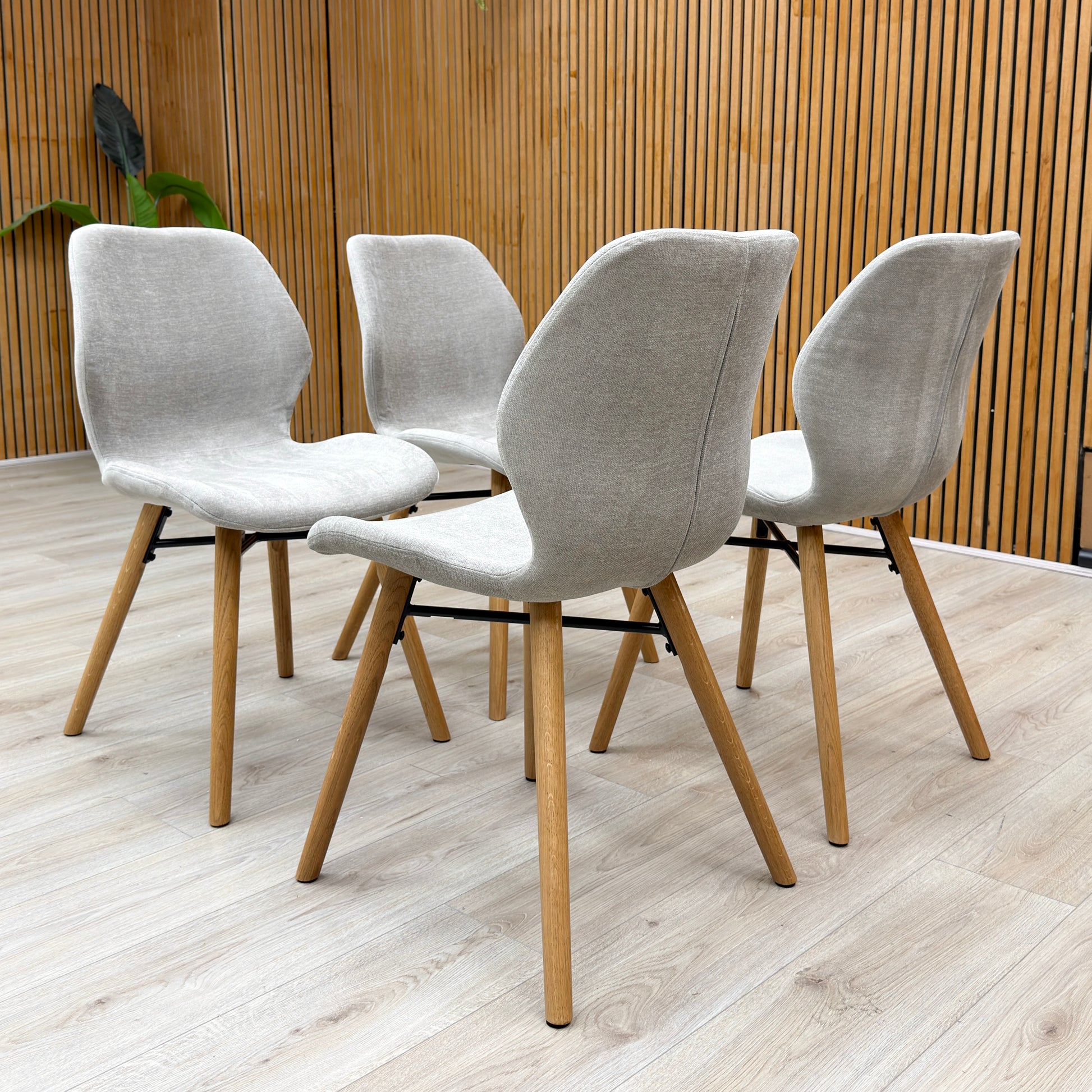 Lifestyle view of the Stockholm upholstered dining chairs, highlighting the soft-sheen lacquer finish and elegant curved back.