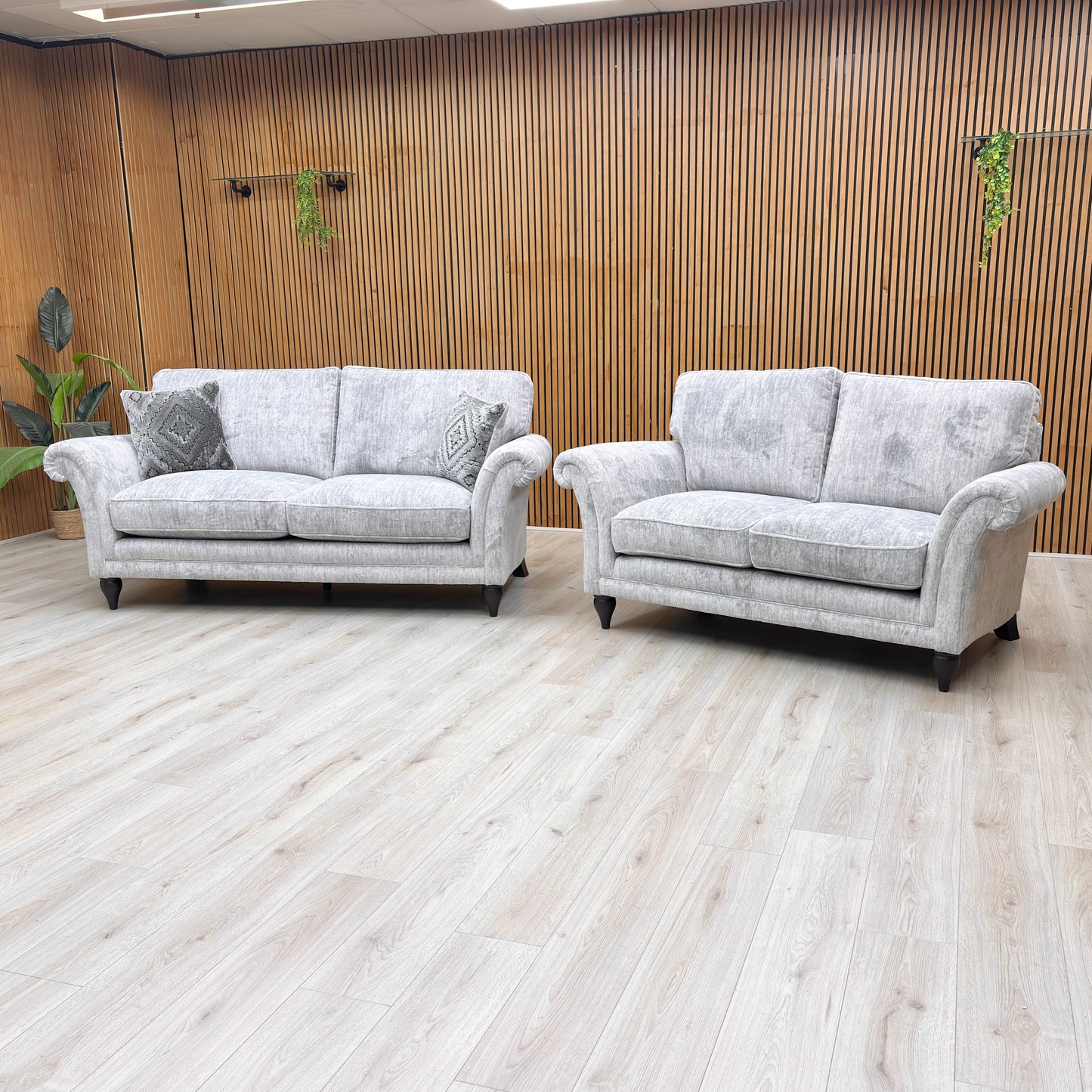 Angled view of the sofa, focusing on the sweeping rolled arms and the solid turned wood legs with a polished mahogany finish.