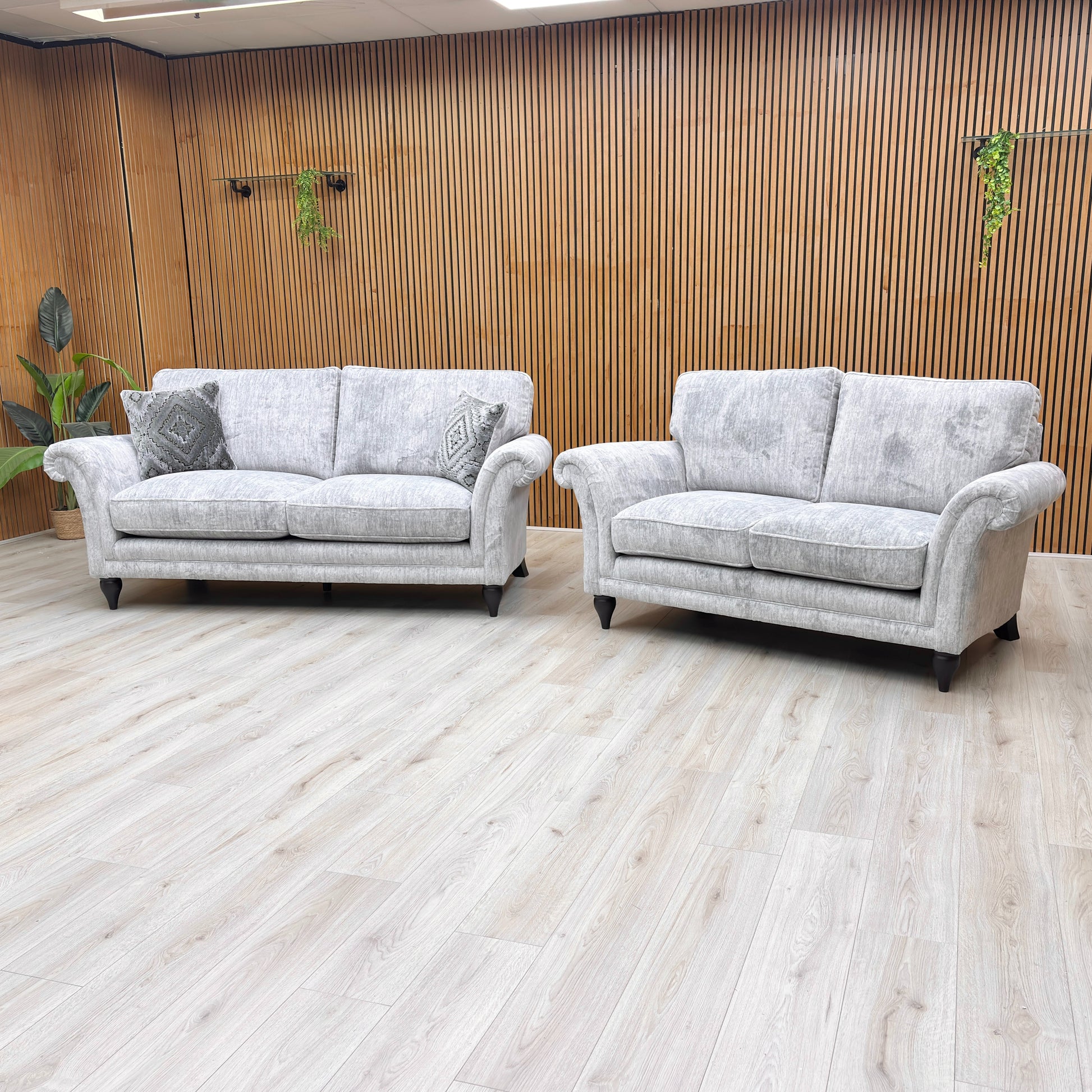 Angled view of the sofa, focusing on the sweeping rolled arms and the solid turned wood legs with a polished mahogany finish.