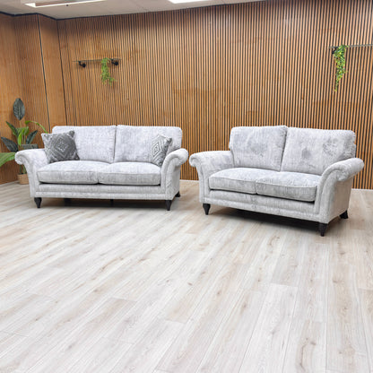Angled view of the sofa, focusing on the sweeping rolled arms and the solid turned wood legs with a polished mahogany finish.