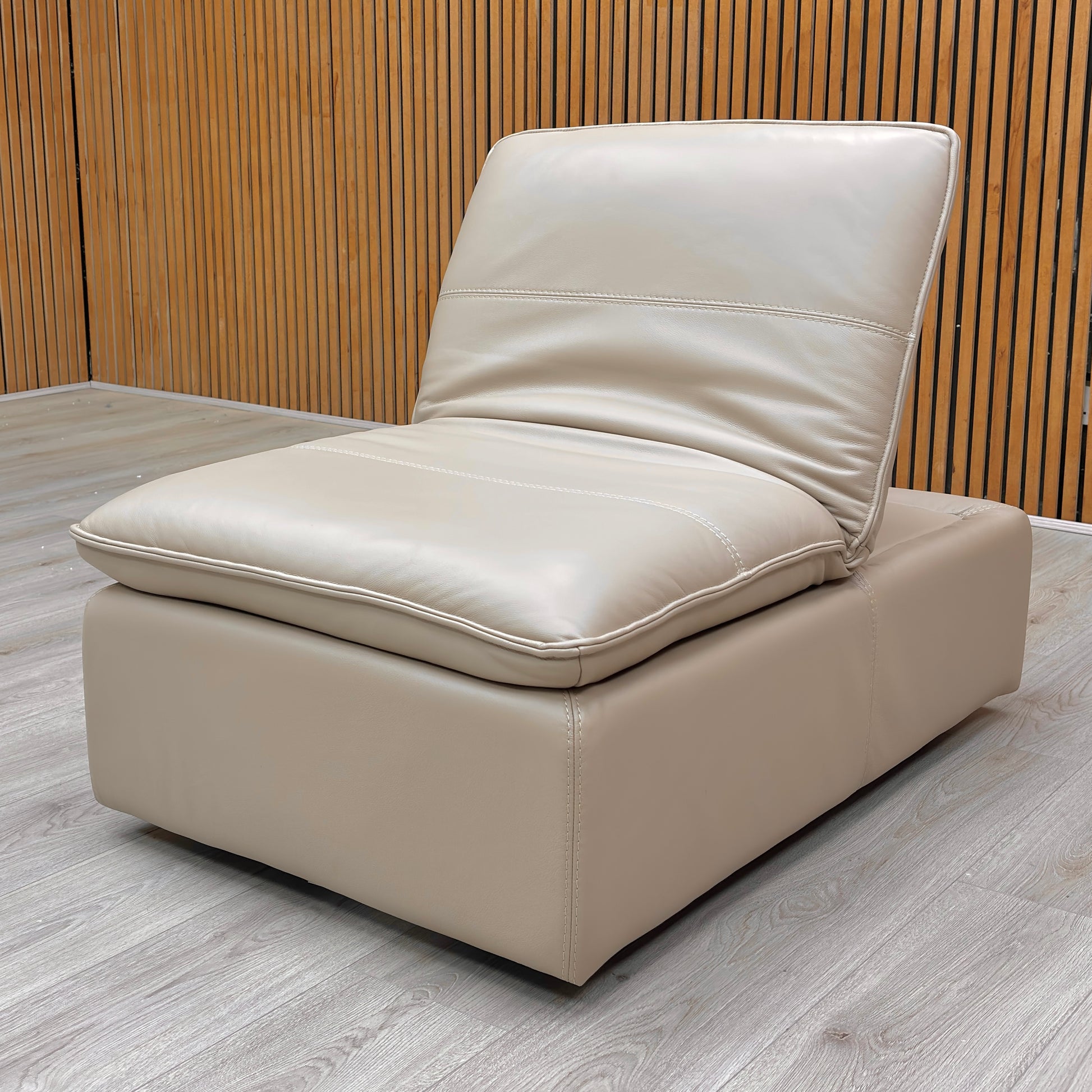 Angled view of the ‘Starlight Express’ Footstool, emphasizing the supple Pebble Cream leather and comfortable medium firmness cushioning.