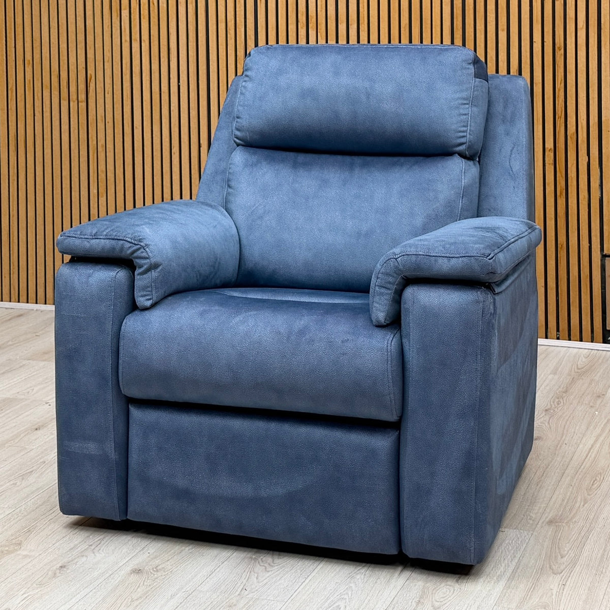 One of the G Plan Thornbury indigo velvet standard chairs from the sofa set against a slatted wooden wall
