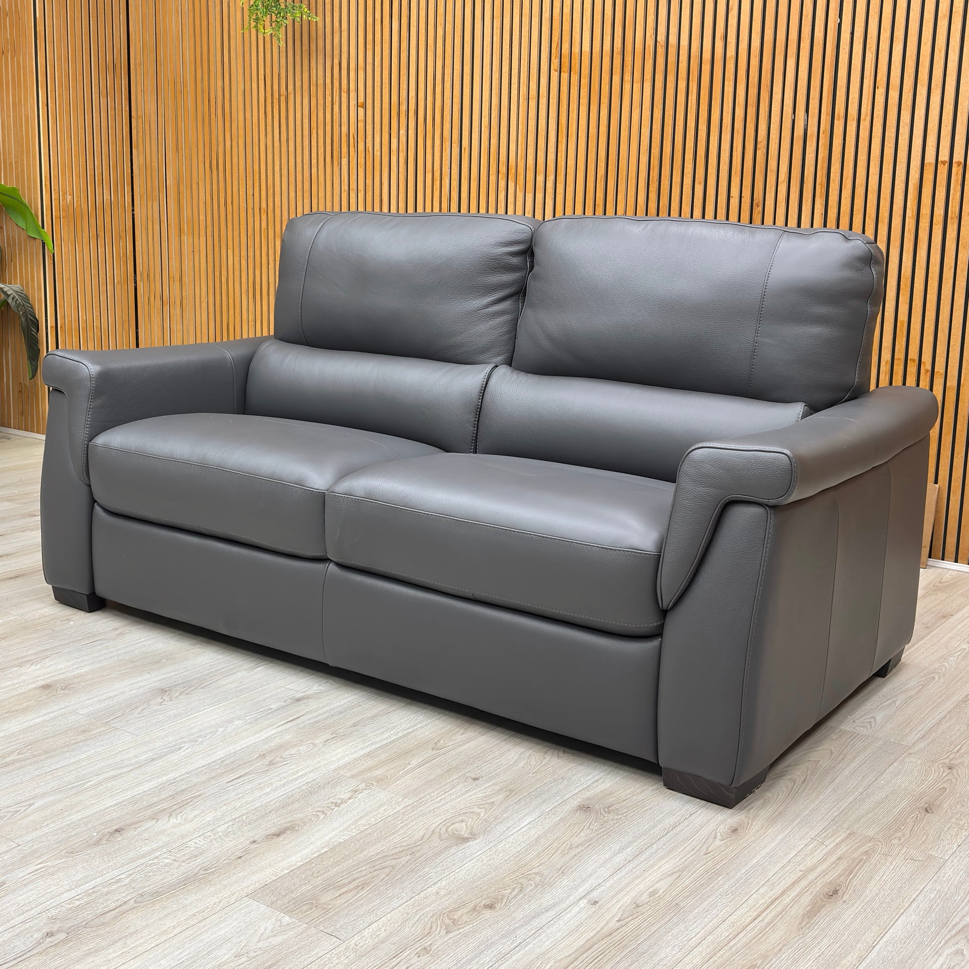 Lifestyle view of the Amore sofa in Medium Grey, showcasing the refined silhouette and smooth leather texture suitable for modern living rooms.