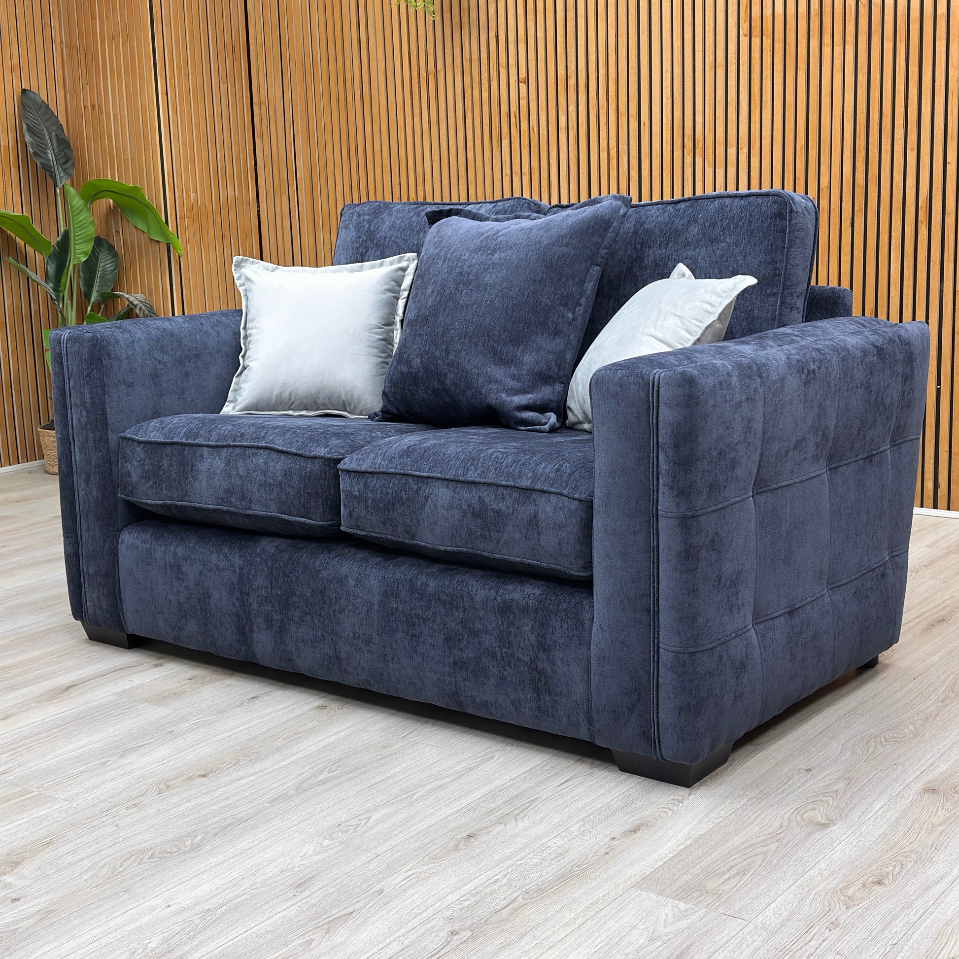 Lifestyle view of the Chelsea denim blue sofa in a cozy, modern living room setting with soft ambient lighting.