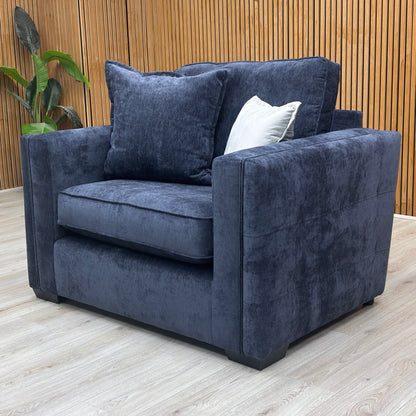 lifestyle view of the Chelsea denim blue love chair in a cozy, modern living room setting.