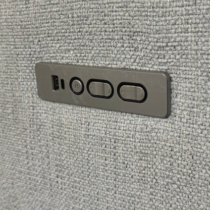 Close-up of the grey metal power control panel for a reclining sofa or chair, embedded into textured fabric.