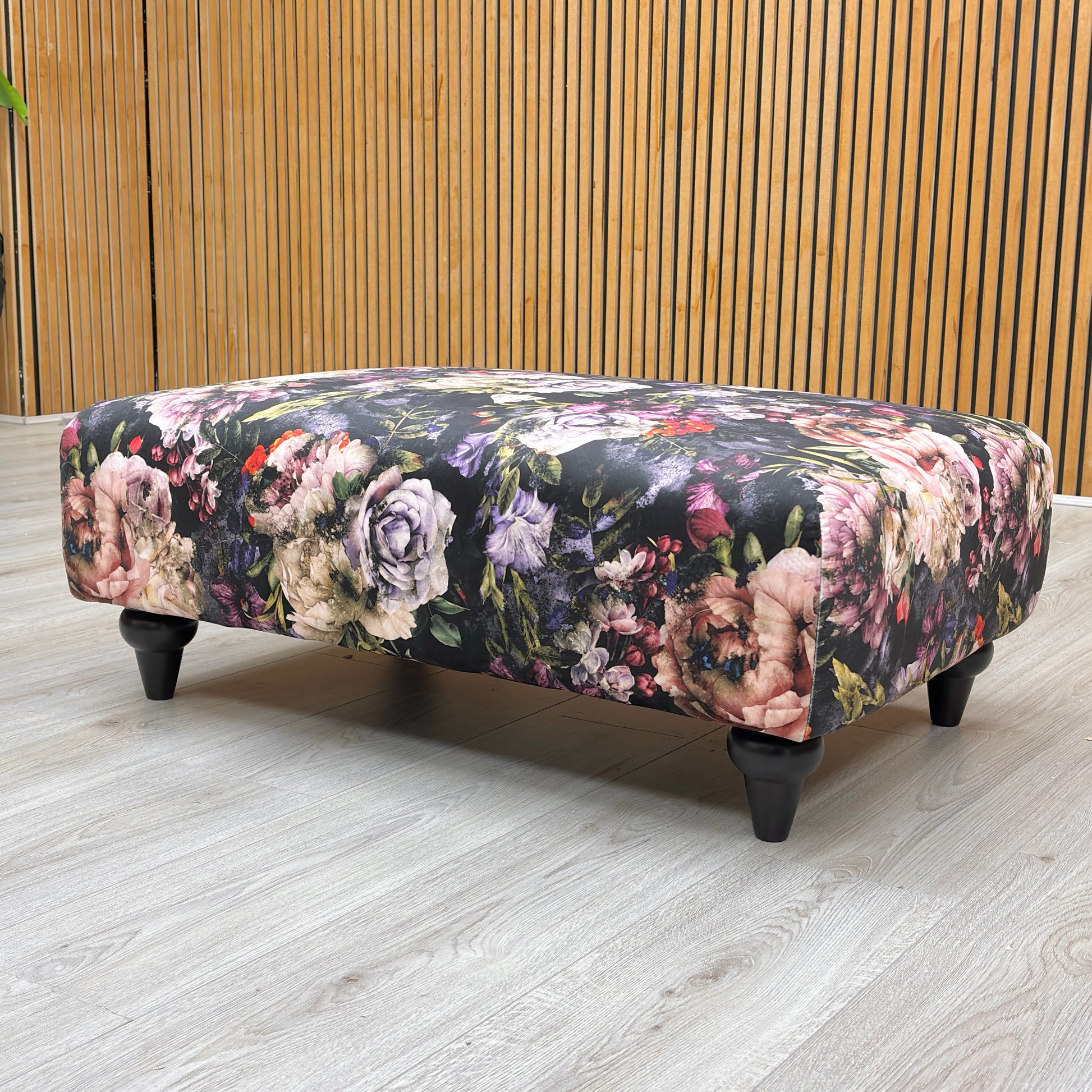 Lifestyle image of the Dame floral footstool styled as a center coffee table in a classic living room.