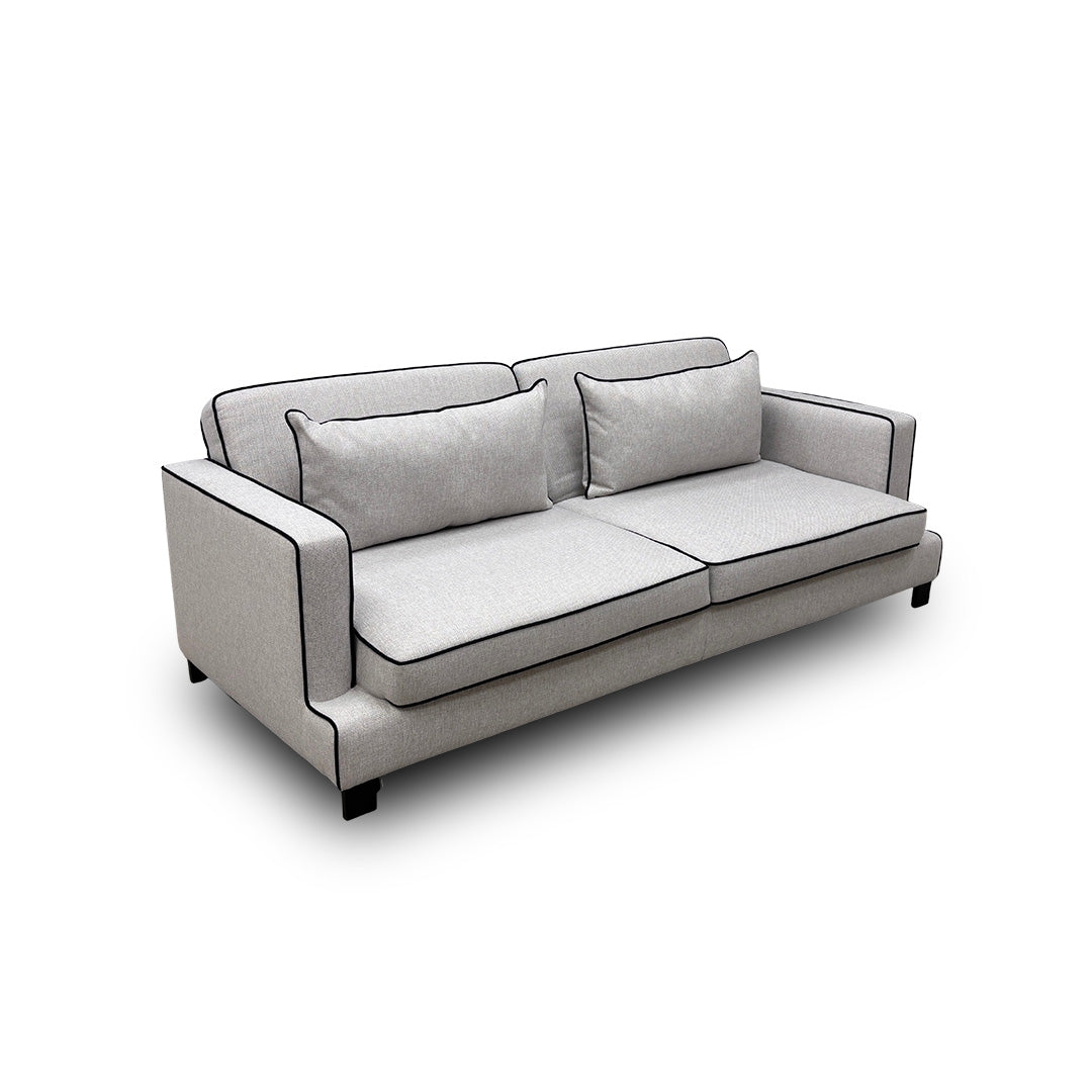 Angled front-left view of the silver 'Demure' Sofa Bed, highlighting the supportive foam back and reversible seat cushions.