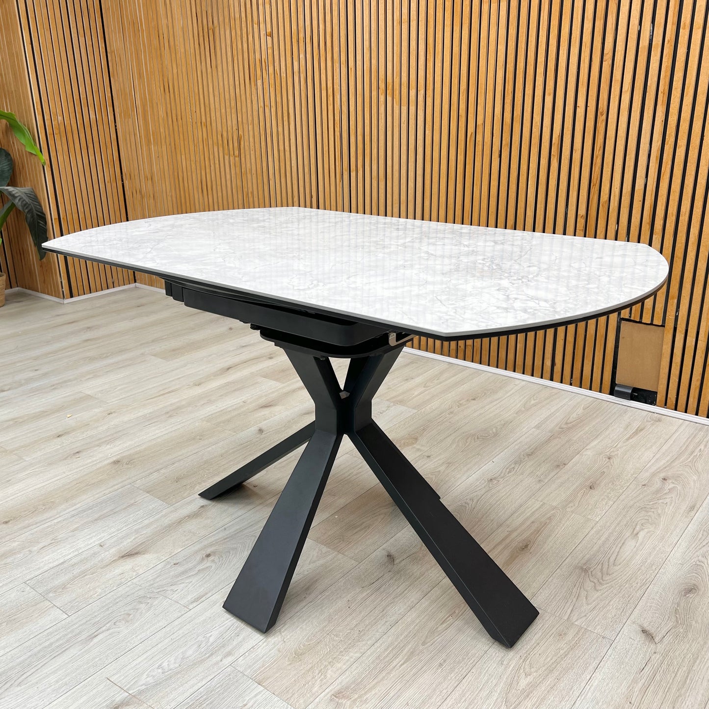 Lifestyle view of the Crete dining table in its compact round form, showcasing the durable textured stone finish and the architectural geometric leg design.