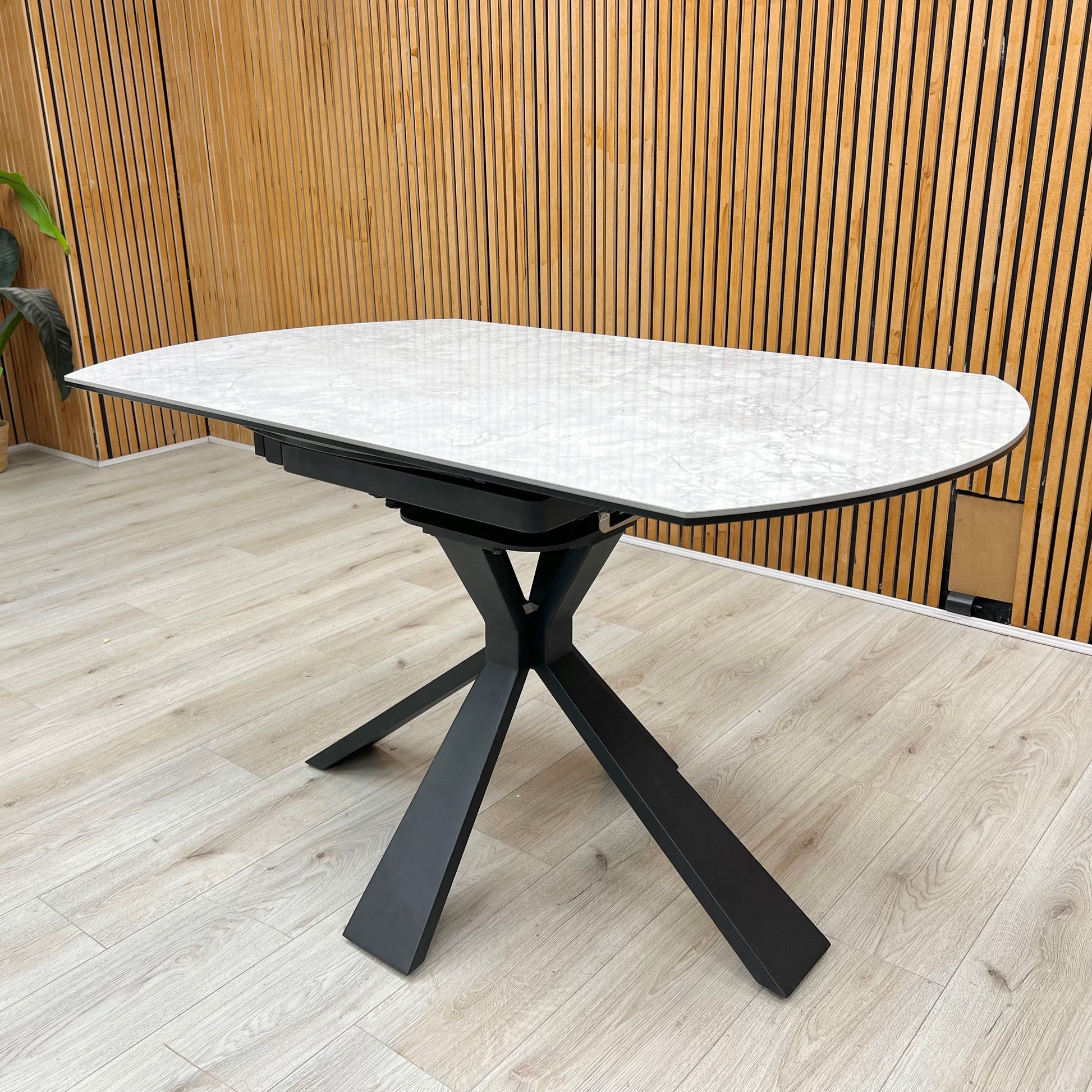 Lifestyle view of the Crete dining table in its compact round form, showcasing the durable textured stone finish and the architectural geometric leg design.