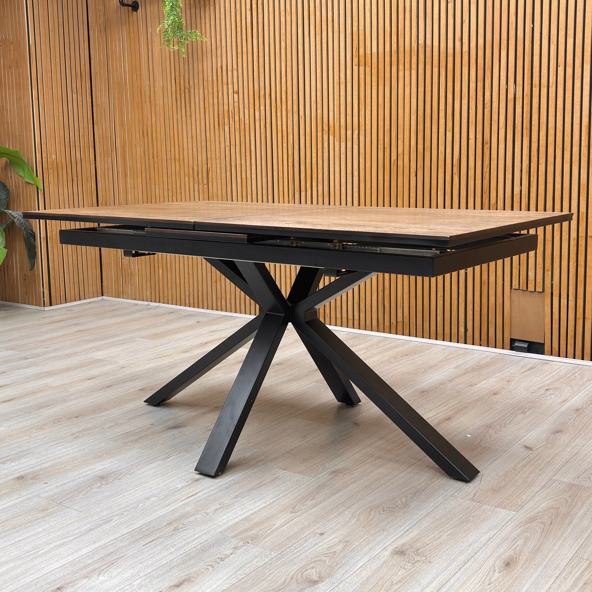 Detail of the stunning black metal star-shaped pedestal base, providing a sturdy and architectural foundation for the oak top.