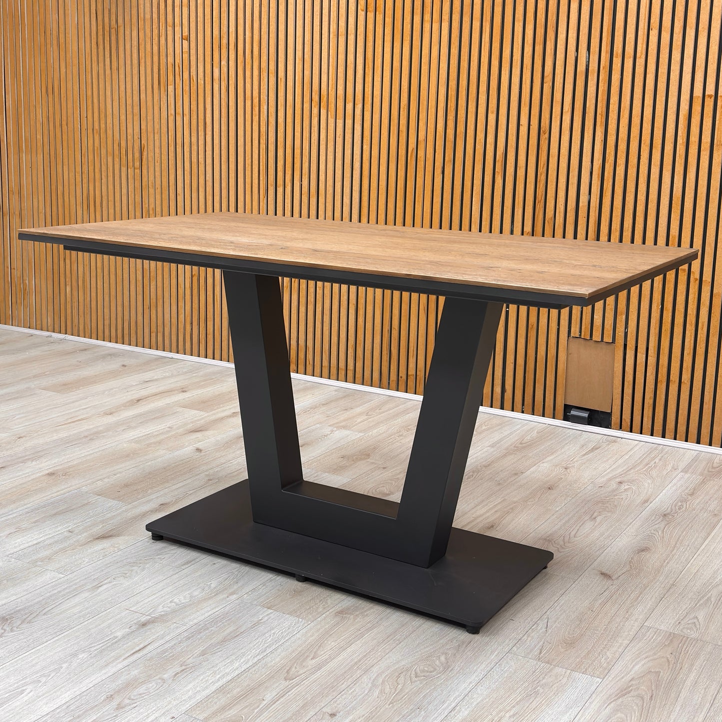 Detailed view of the ergonomic black metal U-shaped base, providing a bold and architectural contrast to the warm oak top.